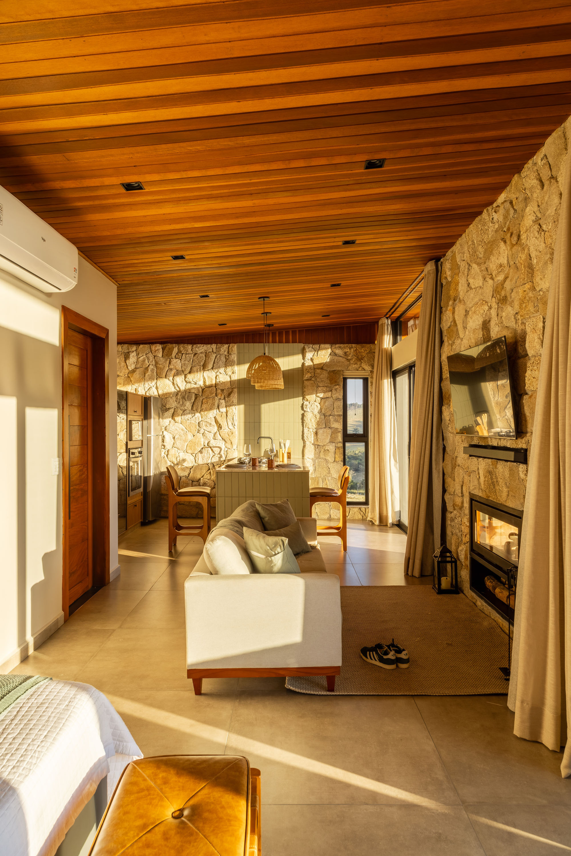 Interior view toward the stone wall and dining area with warm afternoon light filtering through windows
