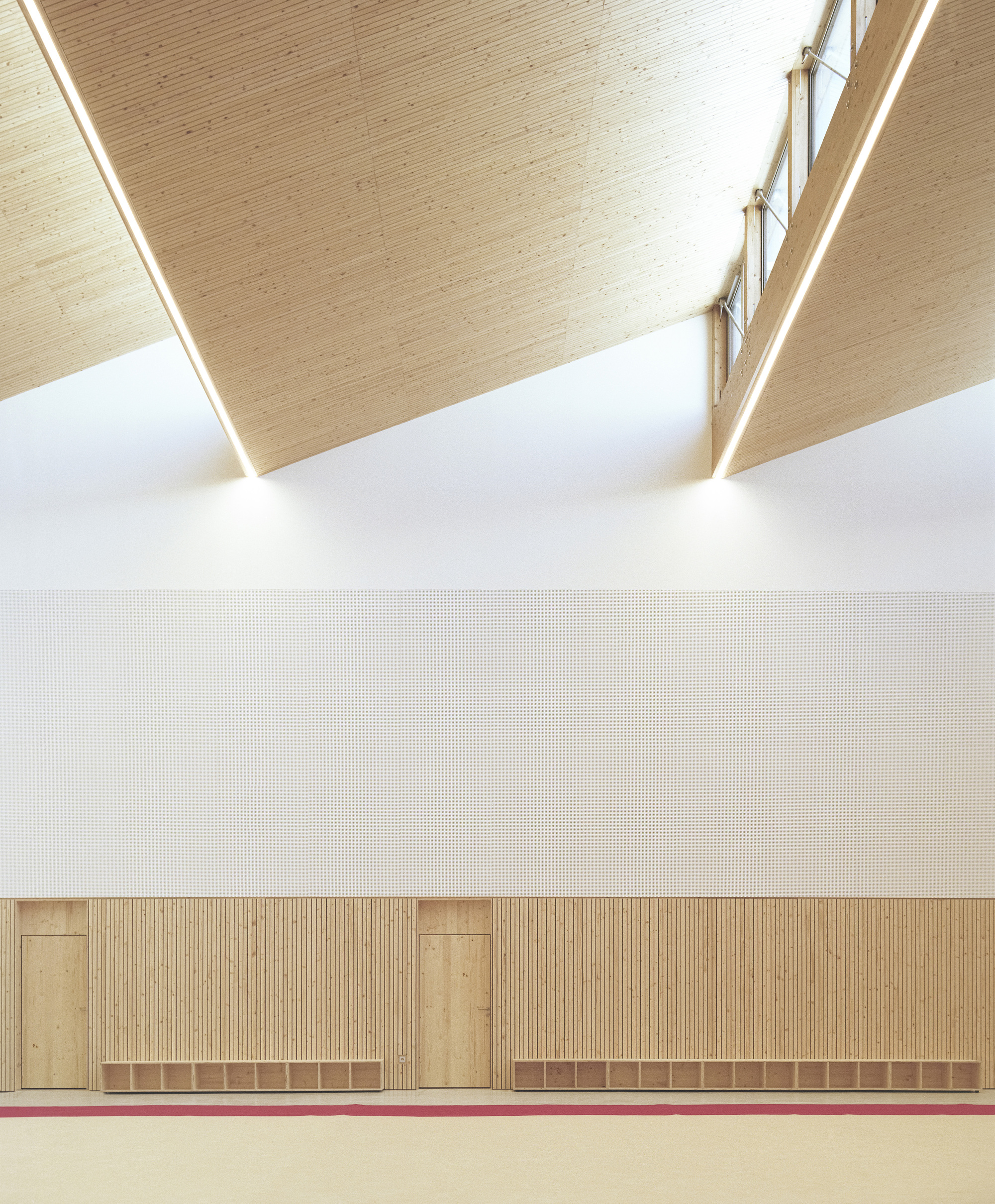 Sawtooth ceiling detail with timber planks, clerestory windows and timber-paneled wainscoting below white wall