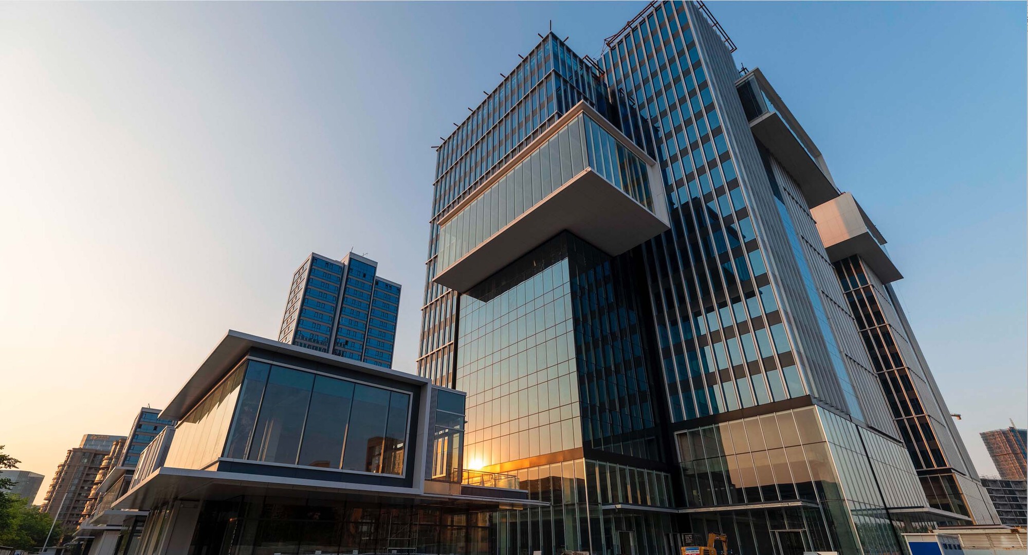 Cantilevered volumes with vertical metal fins and glass curtain wall at twilight