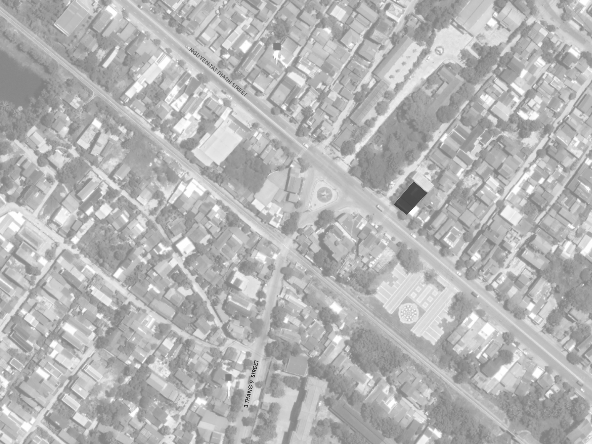 Aerial view showing a rectangular building volume within a dense residential neighborhood grid