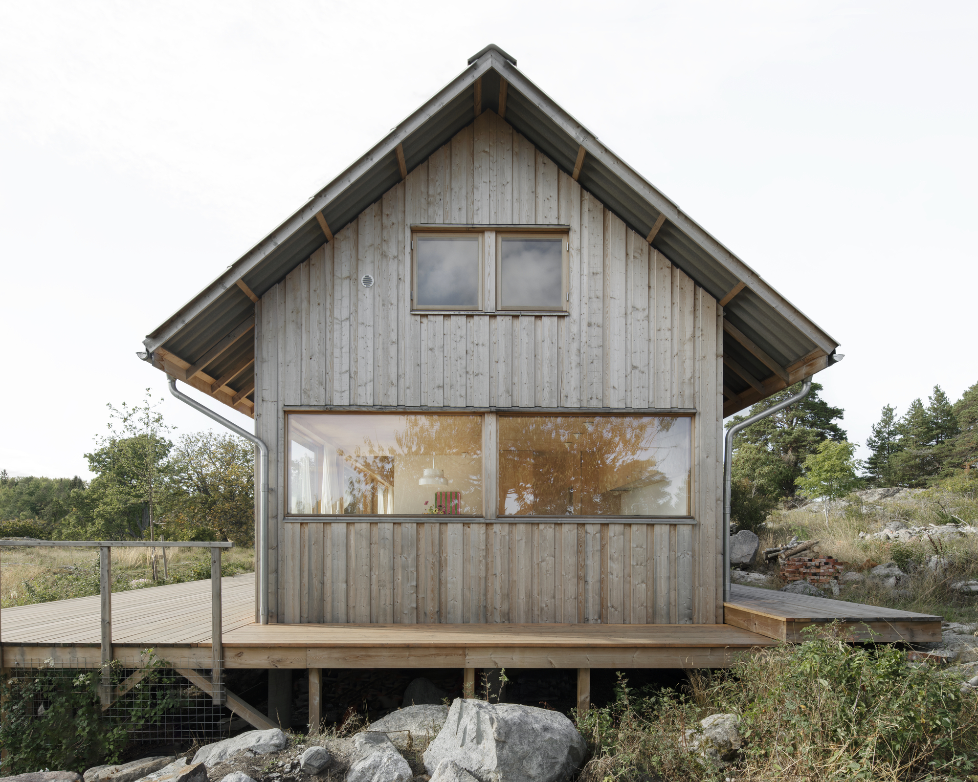 Gable end with vertical timber siding and horizontal strip window on an elevated deck platform