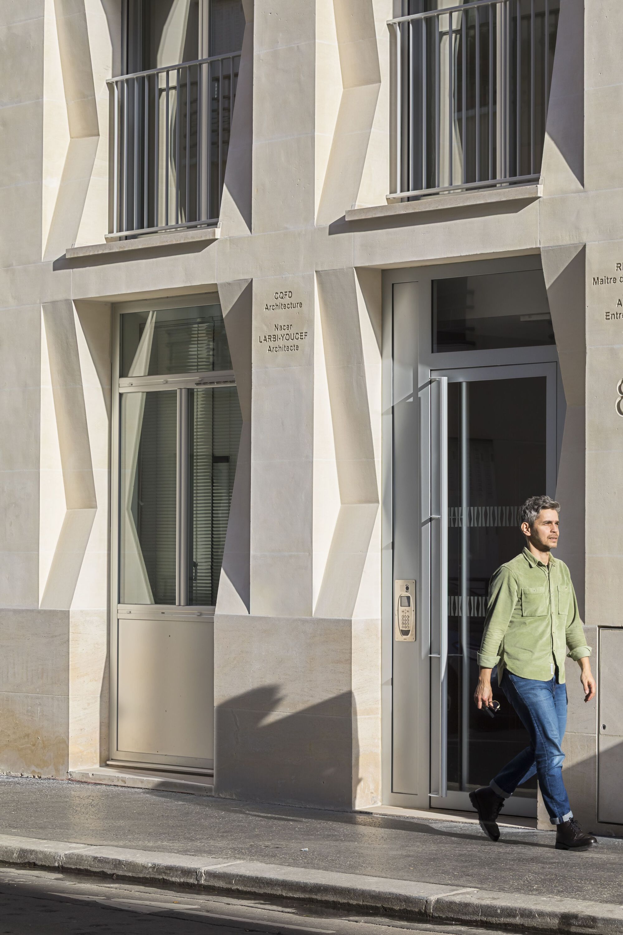 Ground-level entry with glass door as a person in green shirt exits onto the sidewalk