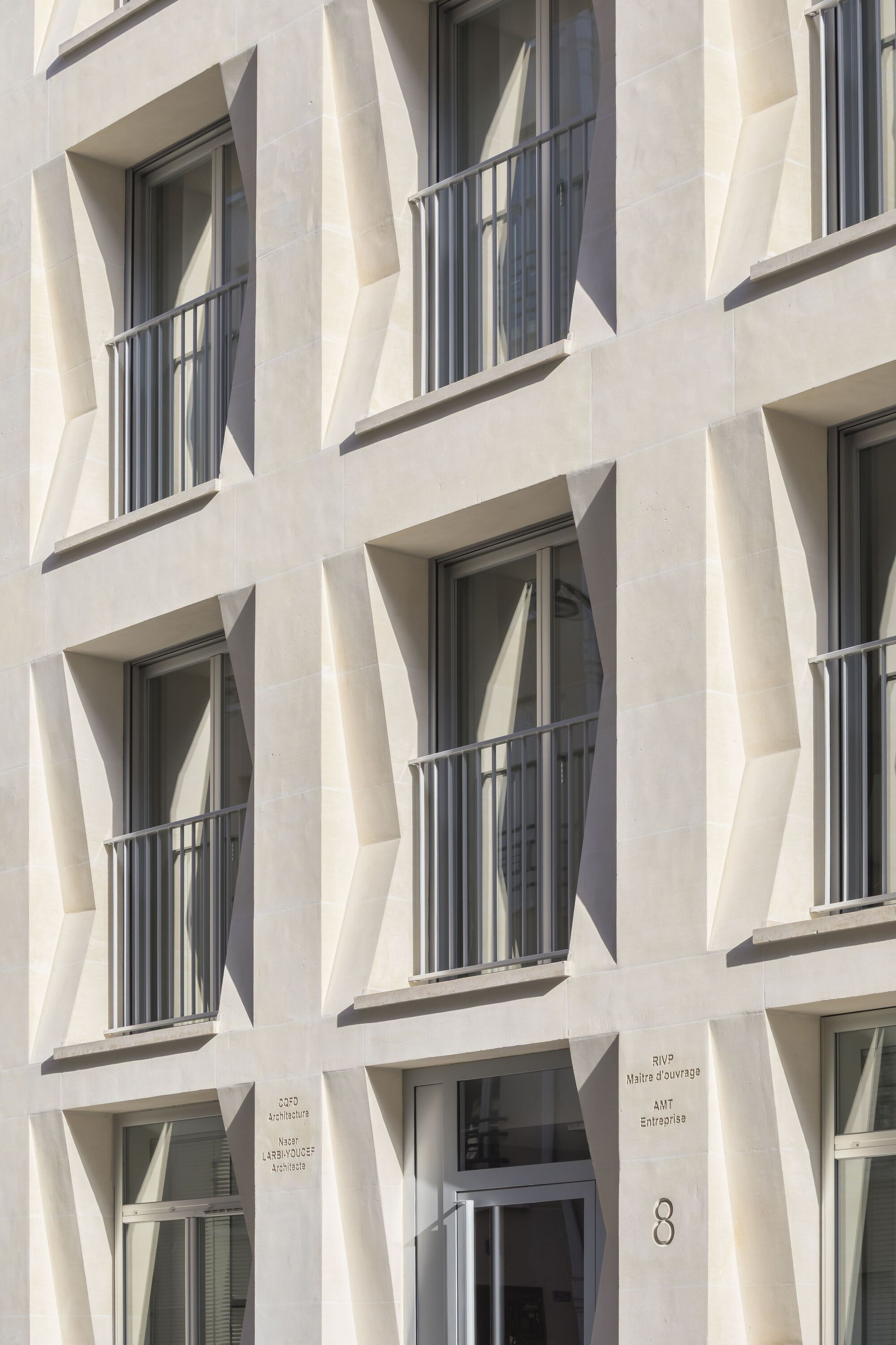 Facade detail showing stacked balconies with metal railings set within diagonal precast frames