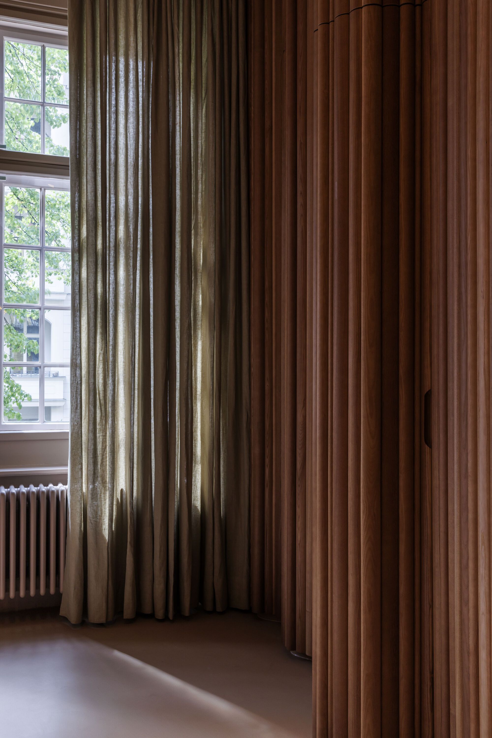 Floor-to-ceiling curtains in beige and brown tones framing a window with natural daylight