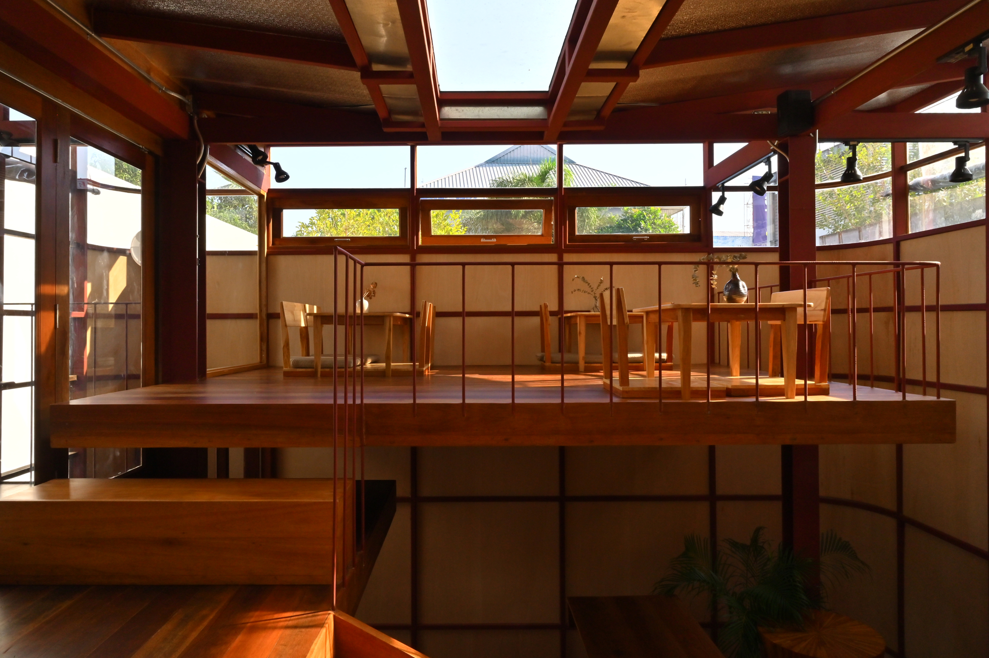 Upper-level timber platform with red steel railings and clerestory windows filtering daylight into the double-height space