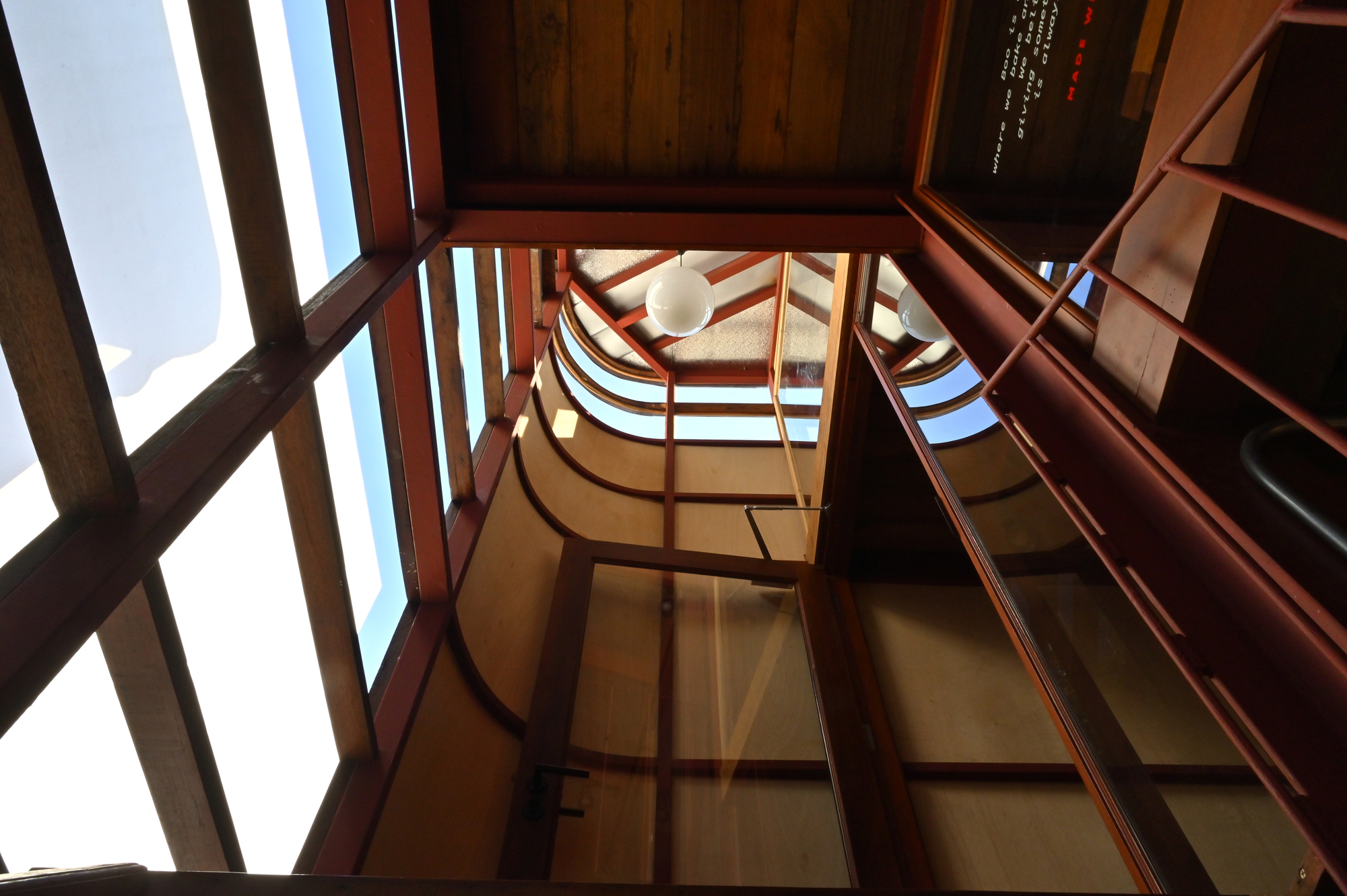 Looking up through the curved stairwell with exposed timber framing and skylight above