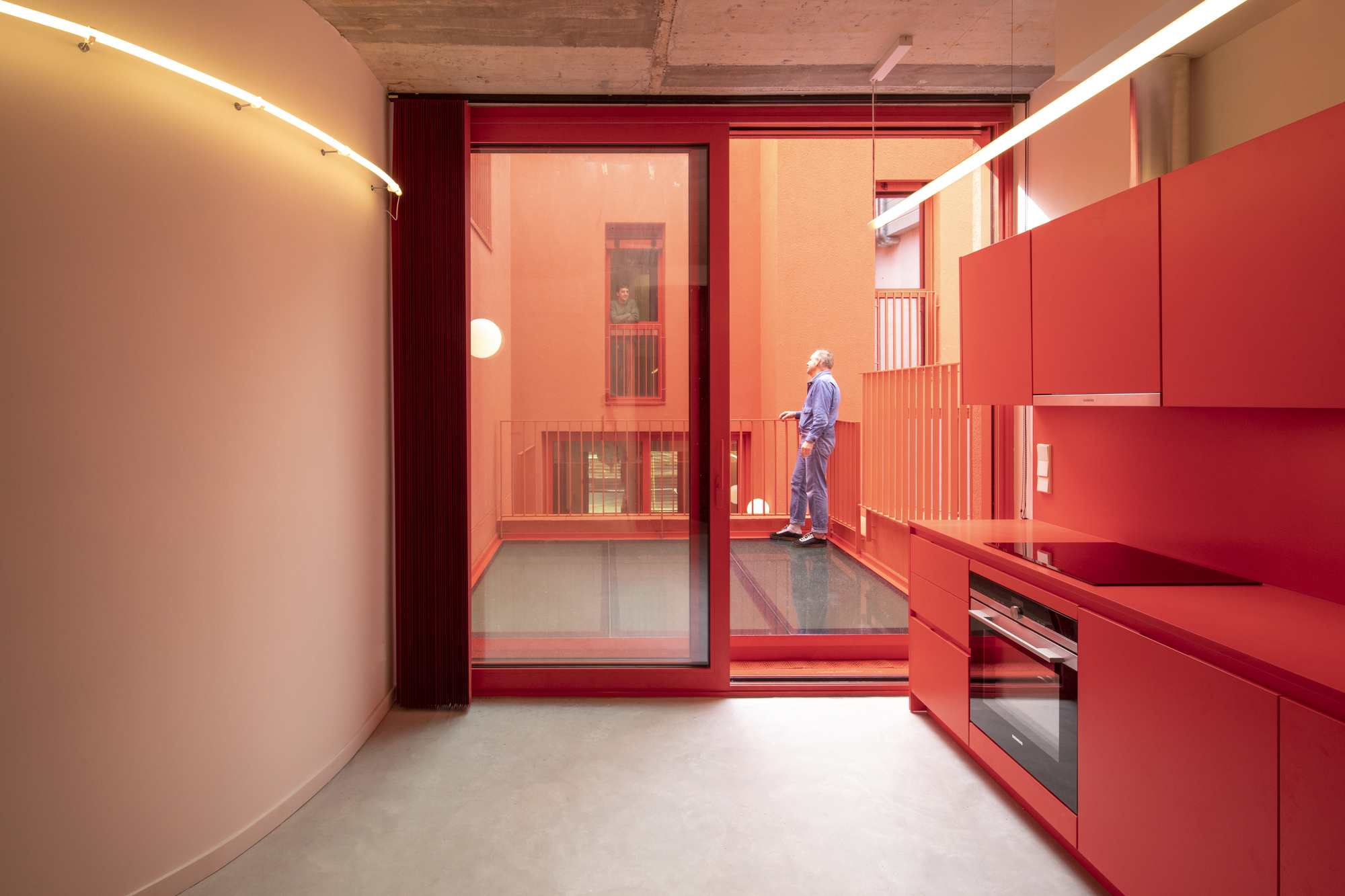Kitchen with red cabinetry and sliding glass door opening to a terrace with timber ceiling
