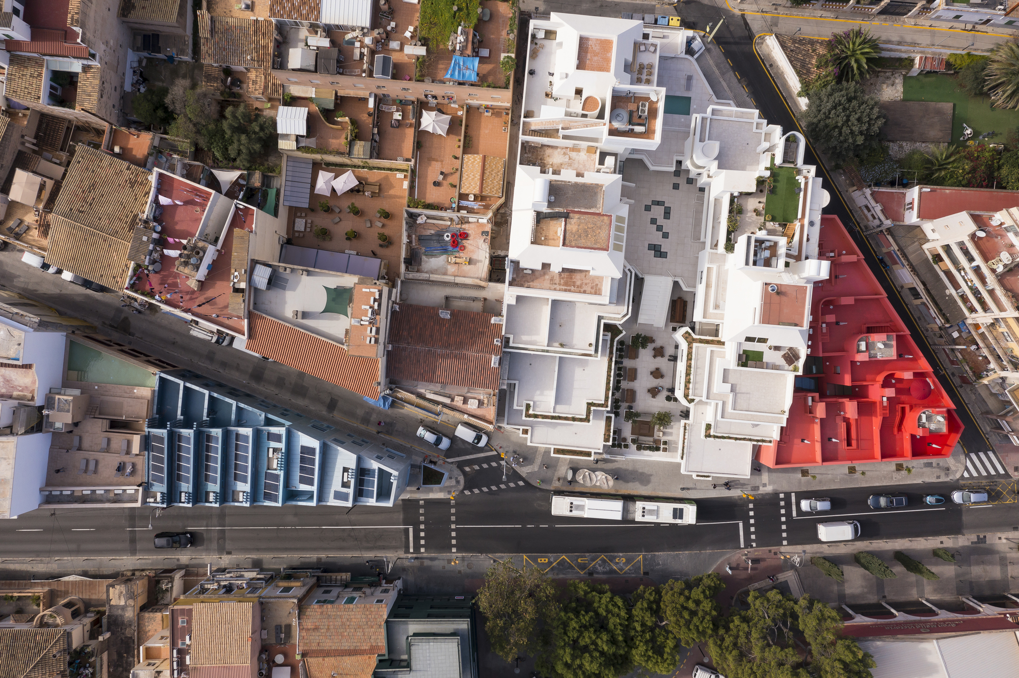Aerial view of clustered white rooftops meeting a red building and street intersection below