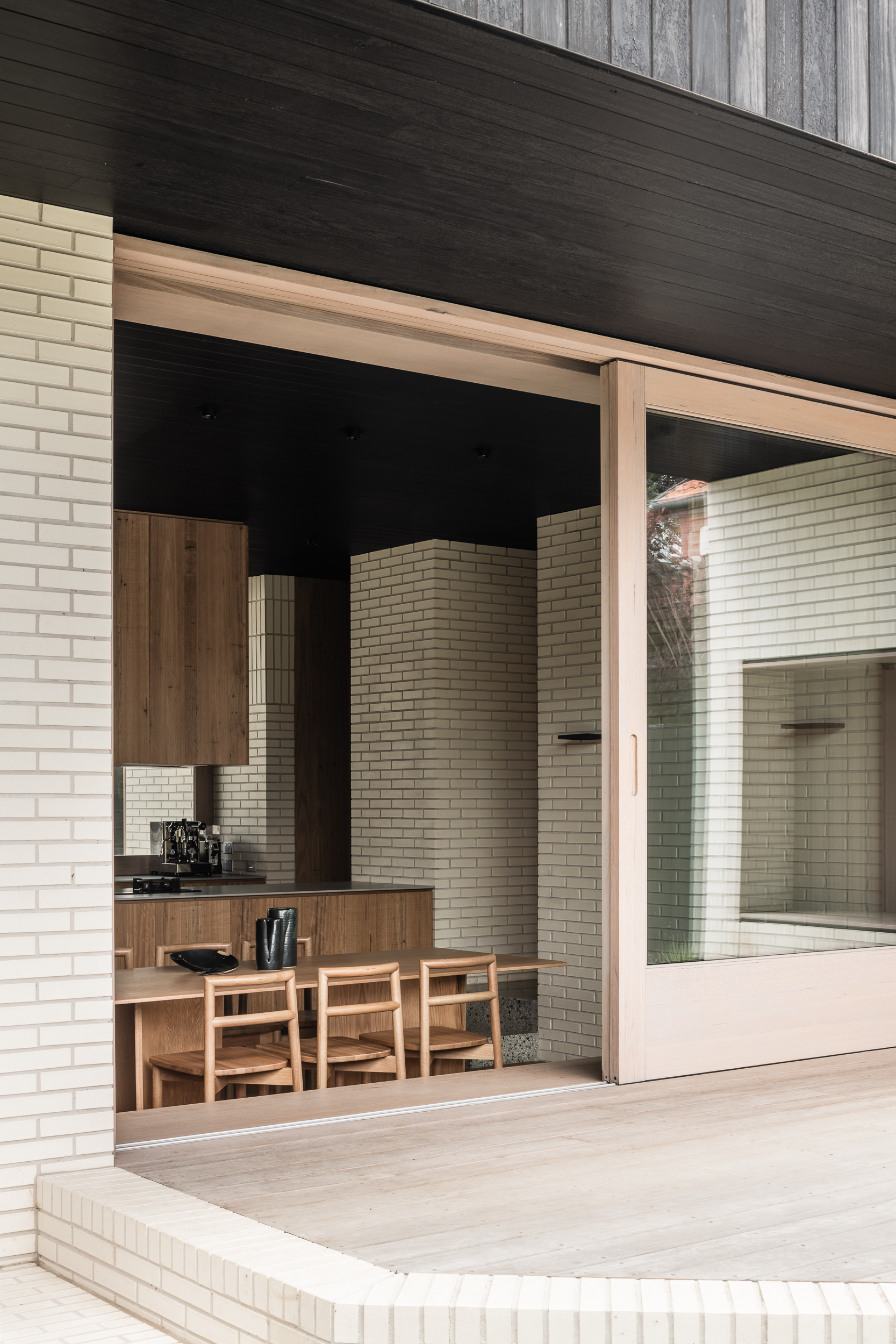 Framed opening with timber surround revealing dining area and white brick courtyard walls beyond