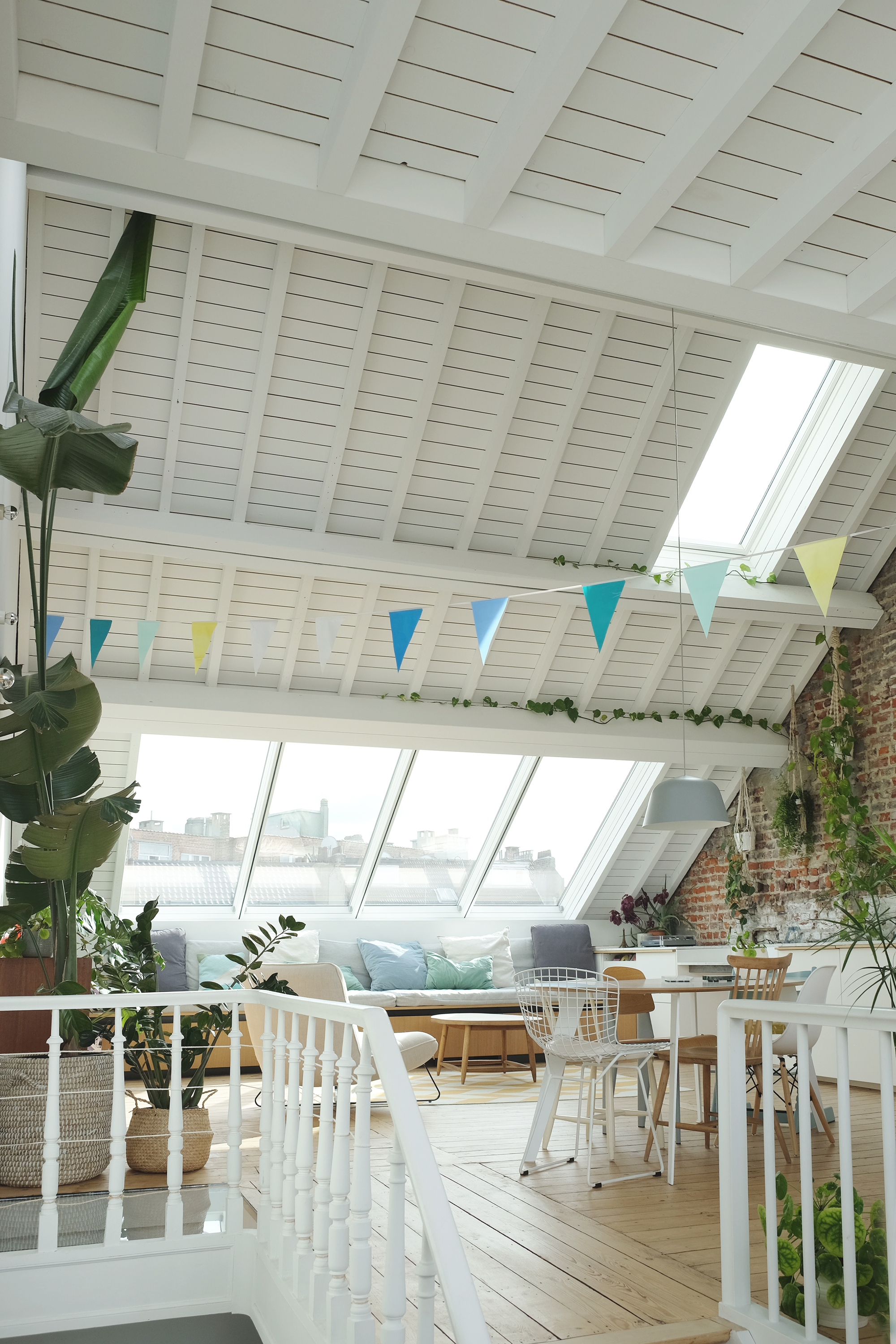 Attic space with painted timber ceiling, angled skylights and colorful fabric bunting strung overhead
