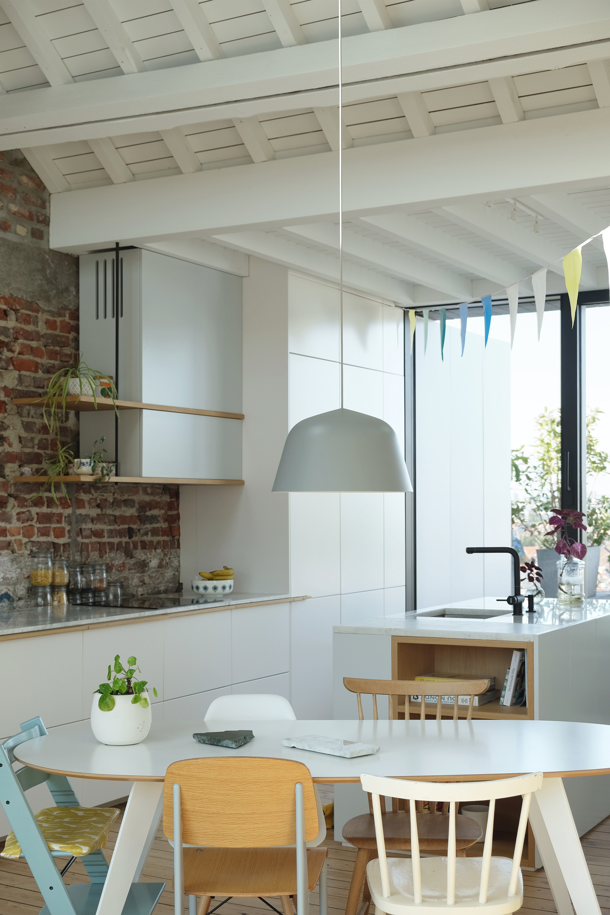 Kitchen with white cabinetry and exposed brick wall under a white-painted coffered timber ceiling