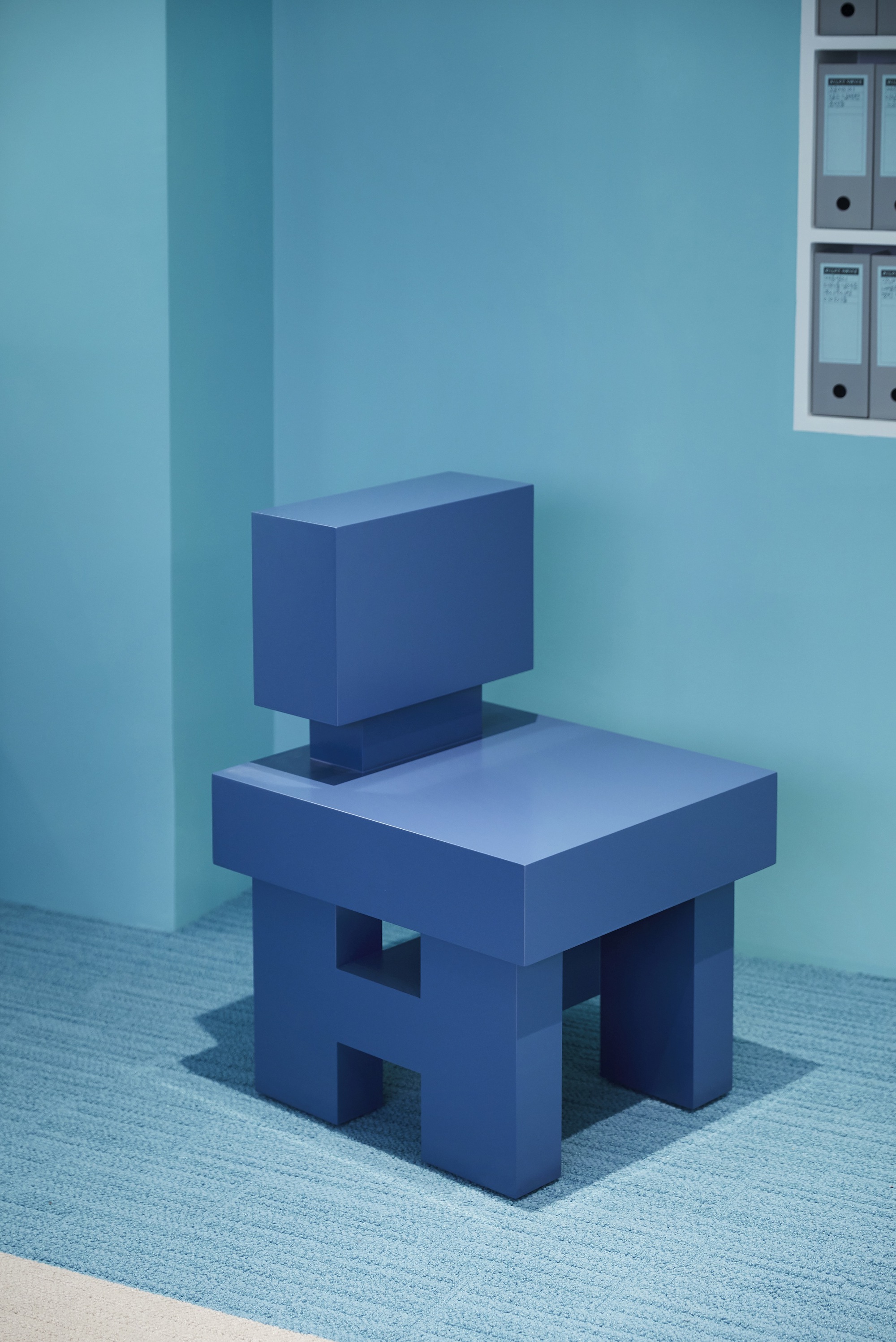 Geometric chair form with rectangular seat and back in solid blue against a corner