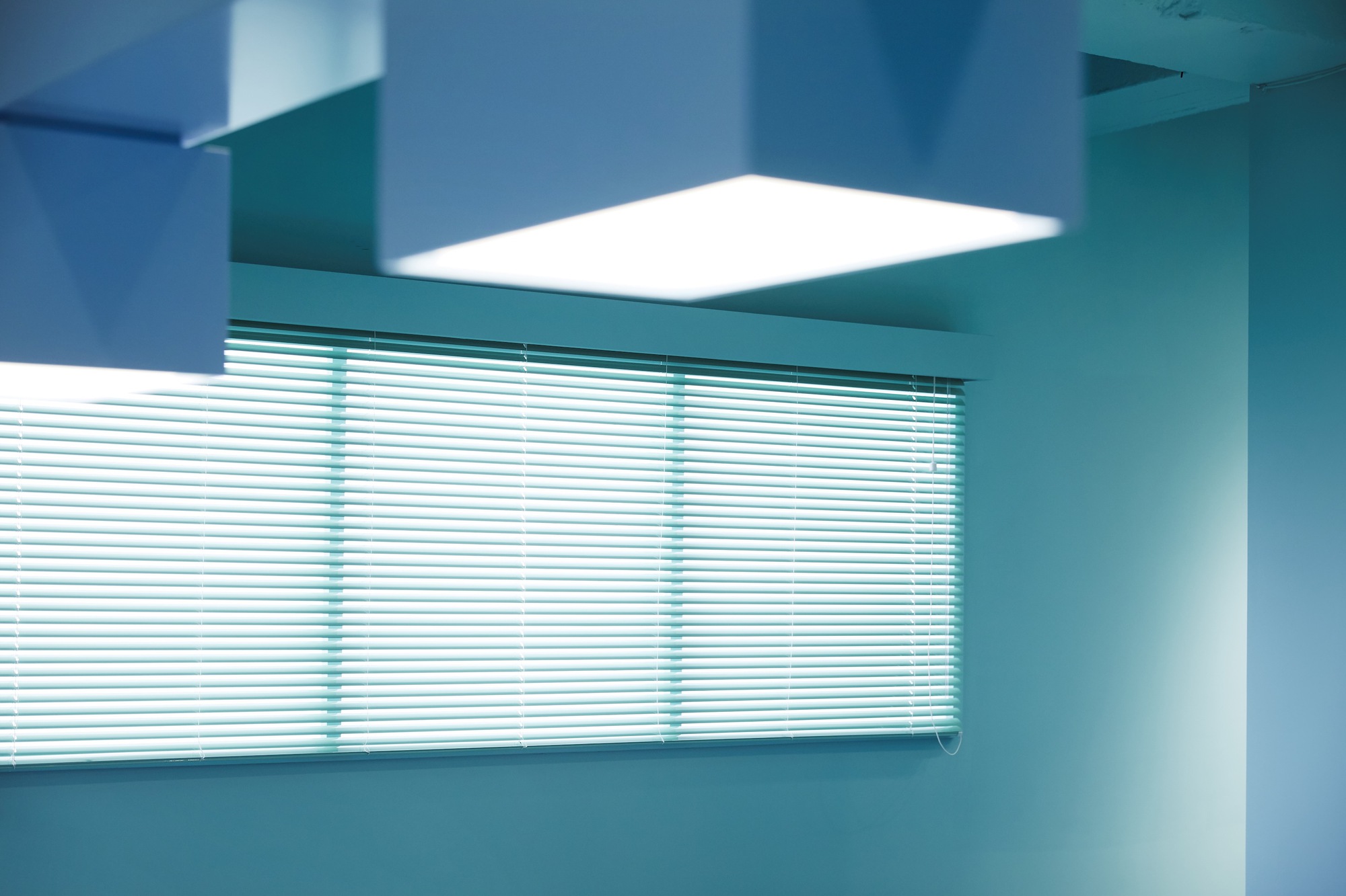 Interior corner with horizontal blinds and recessed skylight casting bright daylight into the room