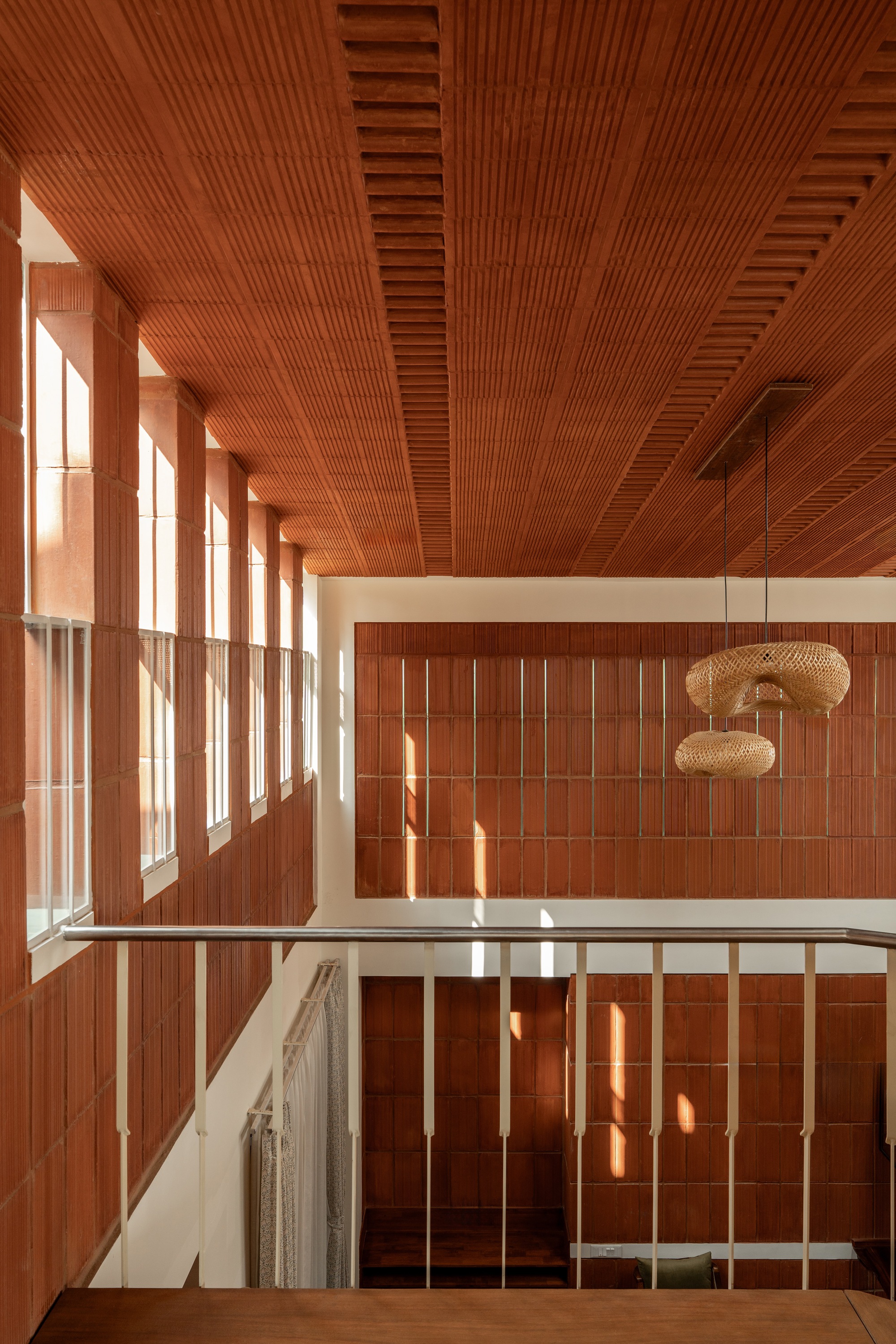 Double-height atrium with timber-slatted ceiling and wall panels flooded with afternoon sunlight