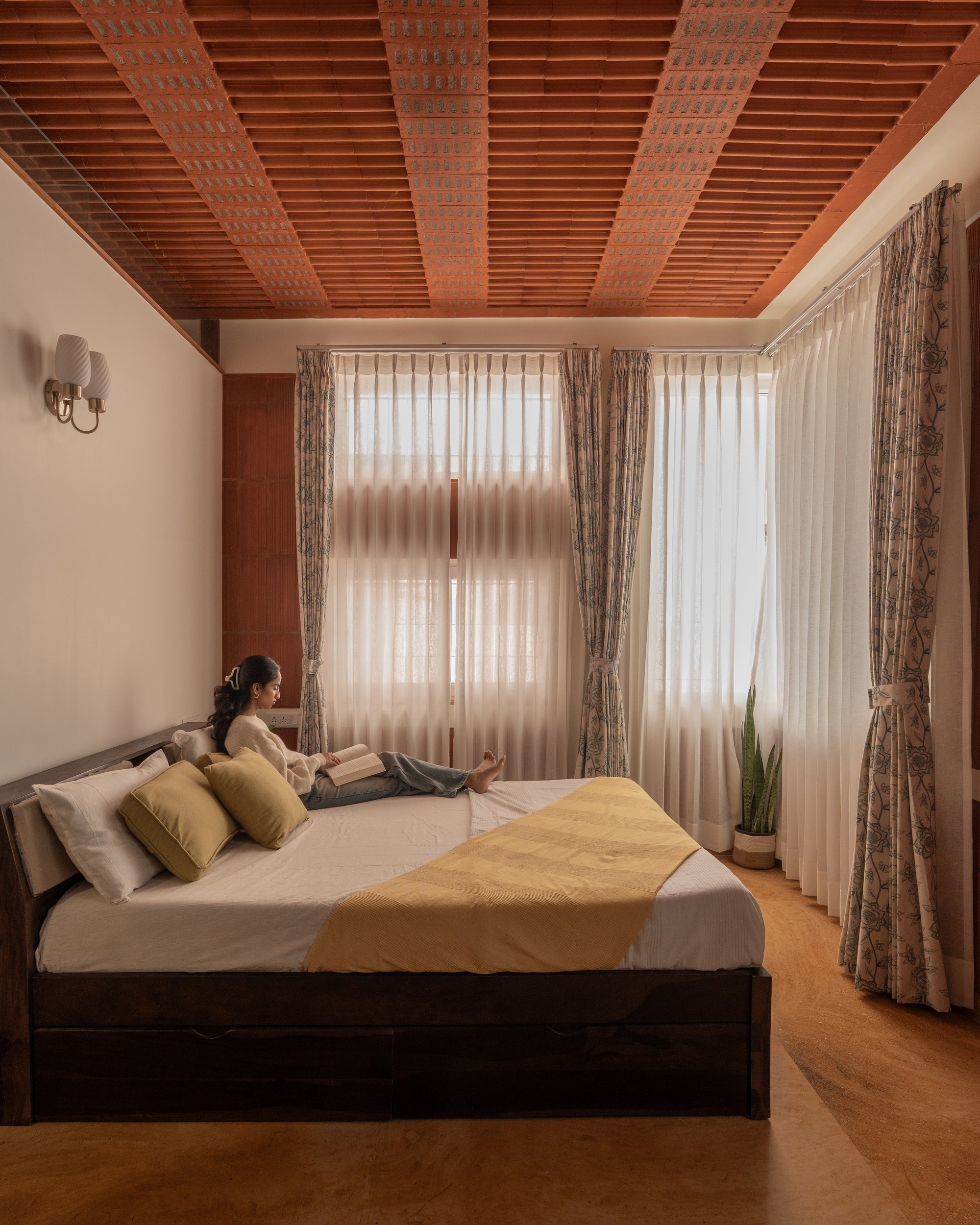 Bedroom with timber-slatted ceiling and sheer curtains diffusing soft morning light