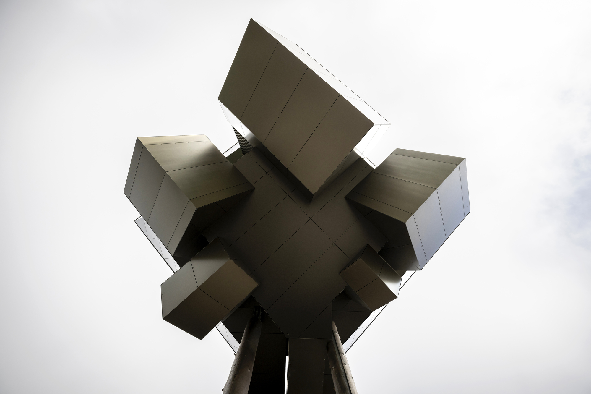 Underside view showing the cruciform arrangement of cantilevered metal-clad volumes meeting at a central support