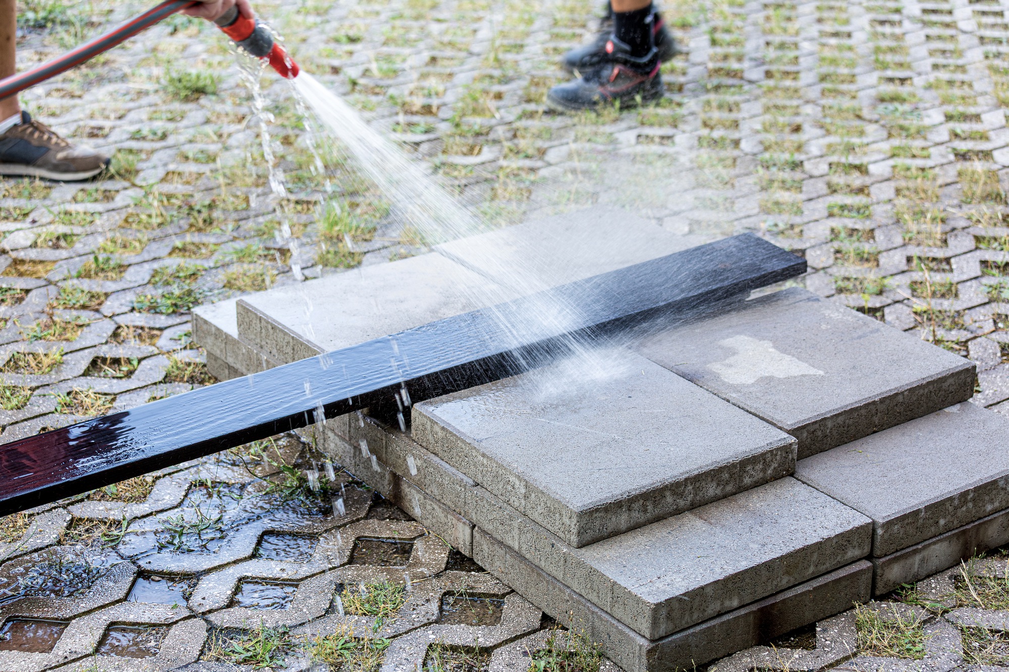 Water being sprayed from a hose onto the charred timber bench during installation or cleaning