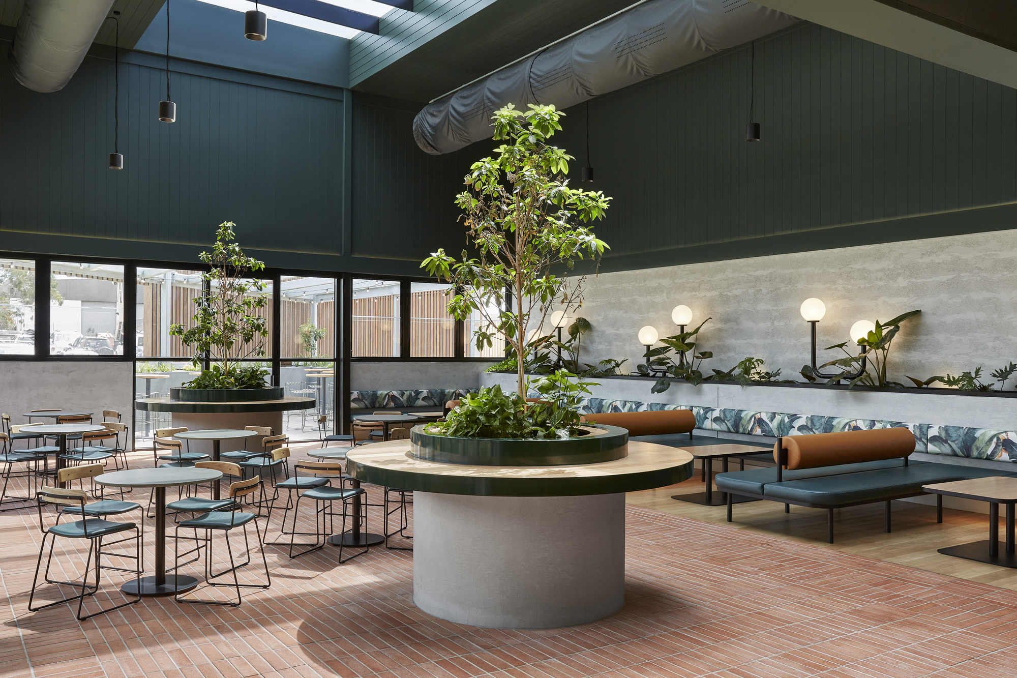 Interior dining area with circular planted planter, terrazzo flooring, and skylights overhead
