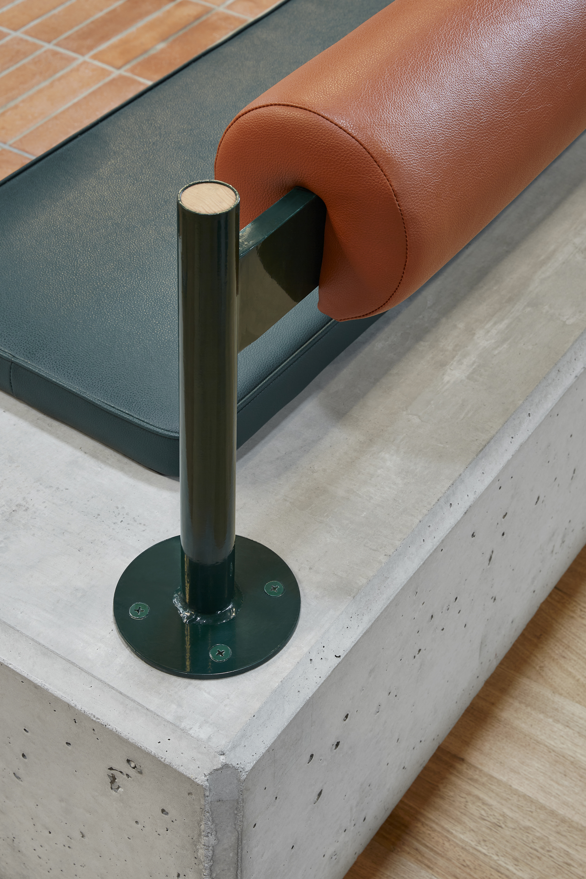 Close-up of tubular steel armrest support anchored to a concrete plinth base