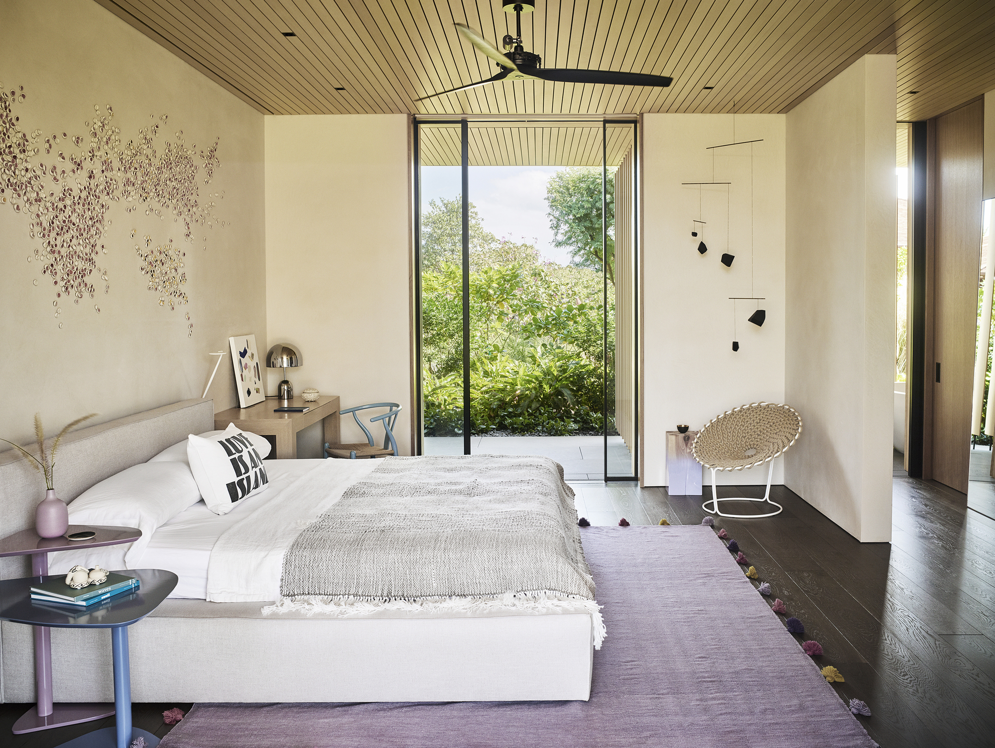 Bedroom with tall glazed door framing view of trees and slatted wood ceiling overhead