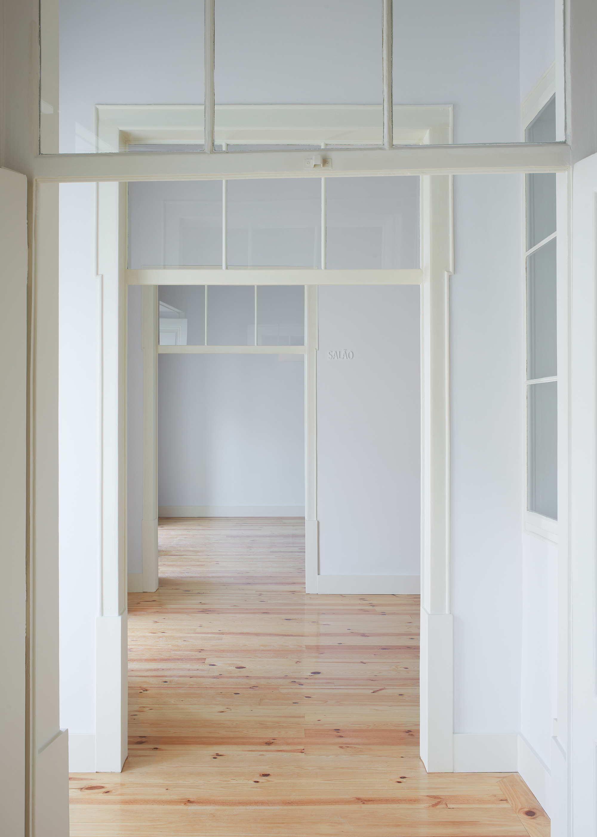 View through a timber-framed doorway with transom windows opening to adjacent rooms