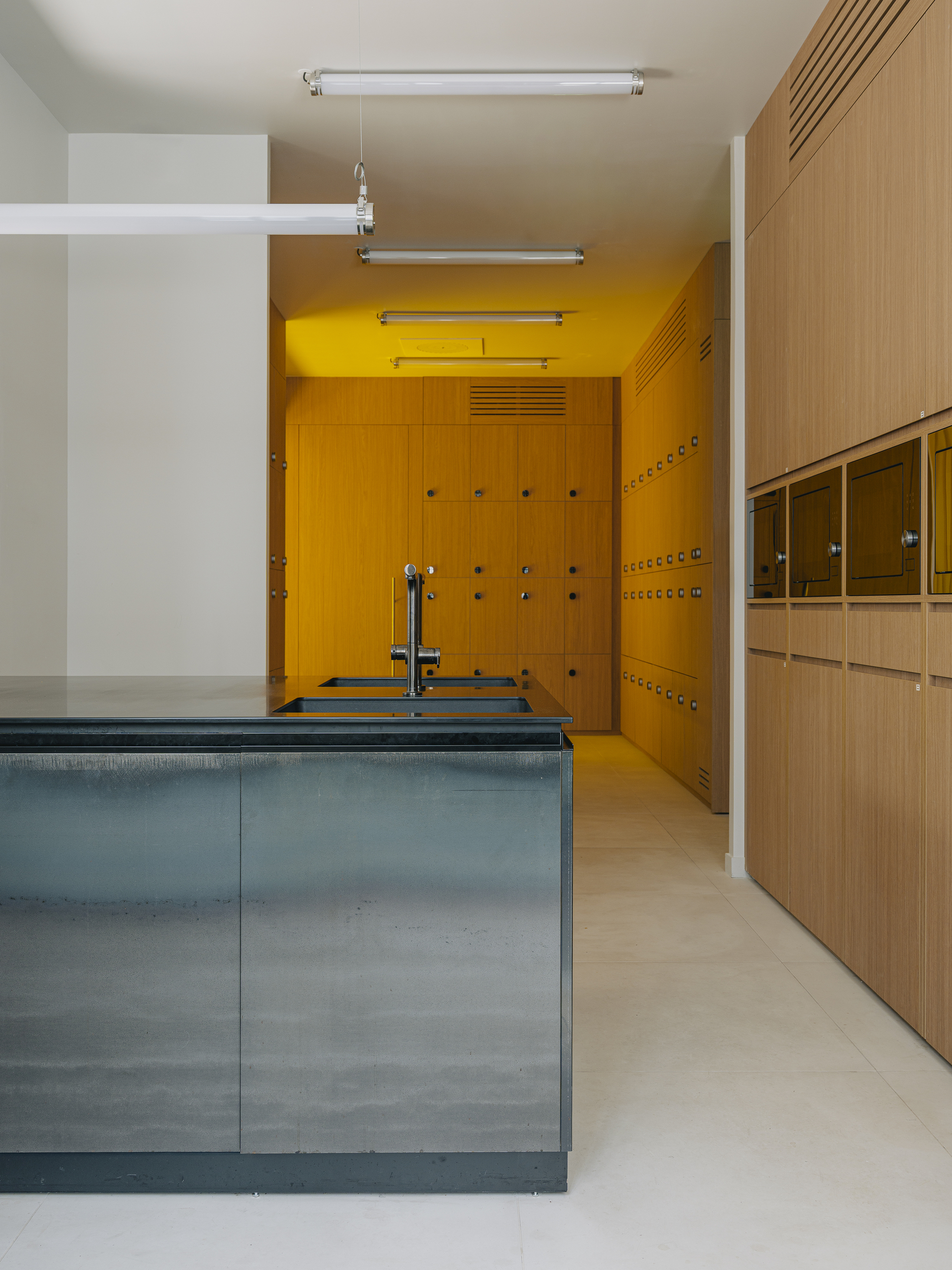 Kitchen with blue metal island beneath yellow locker room framed by timber millwork and white ceiling