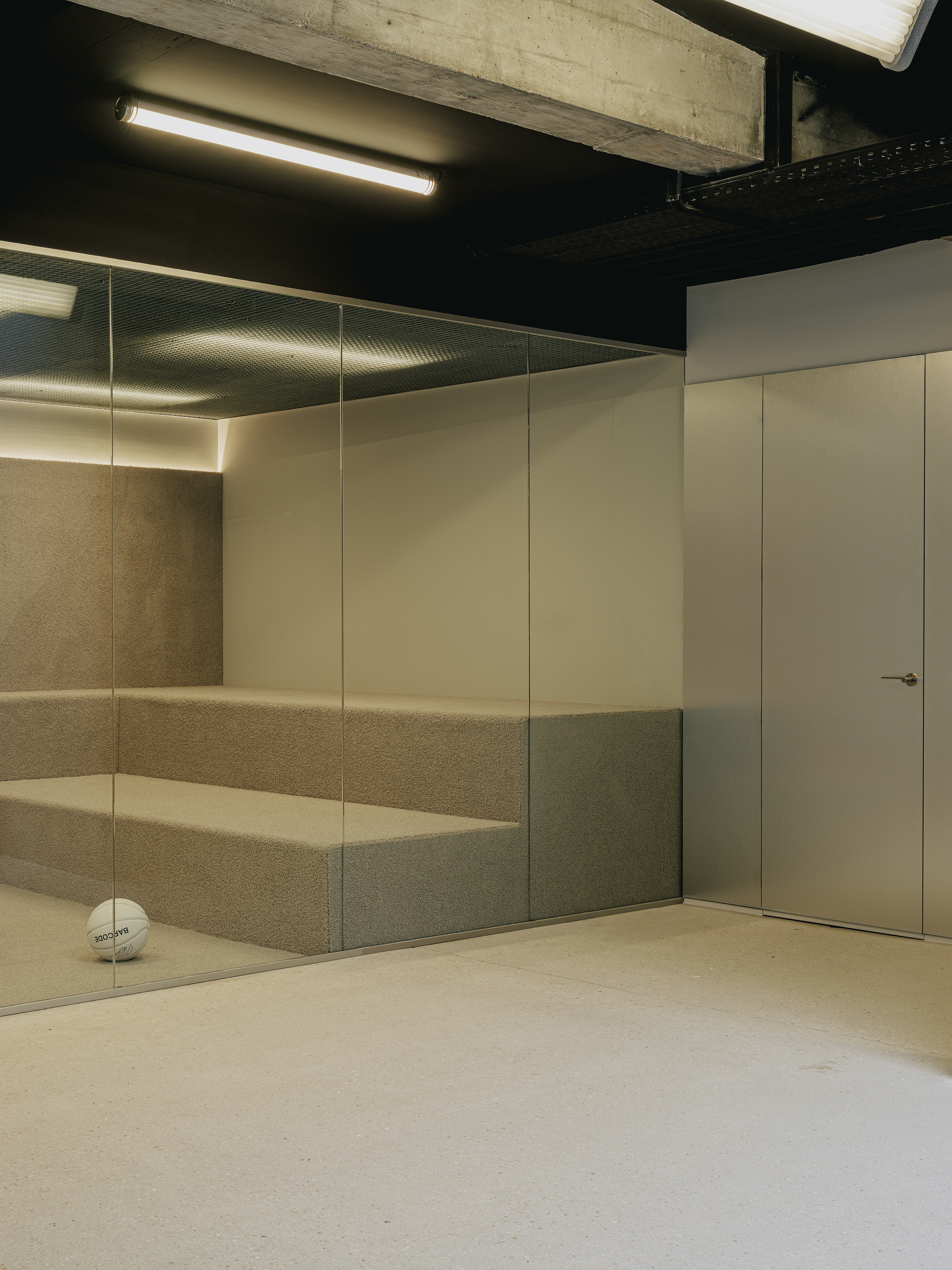 Corner with glass-fronted cork wall niche, flush white door, and black-painted ceiling under concrete beam
