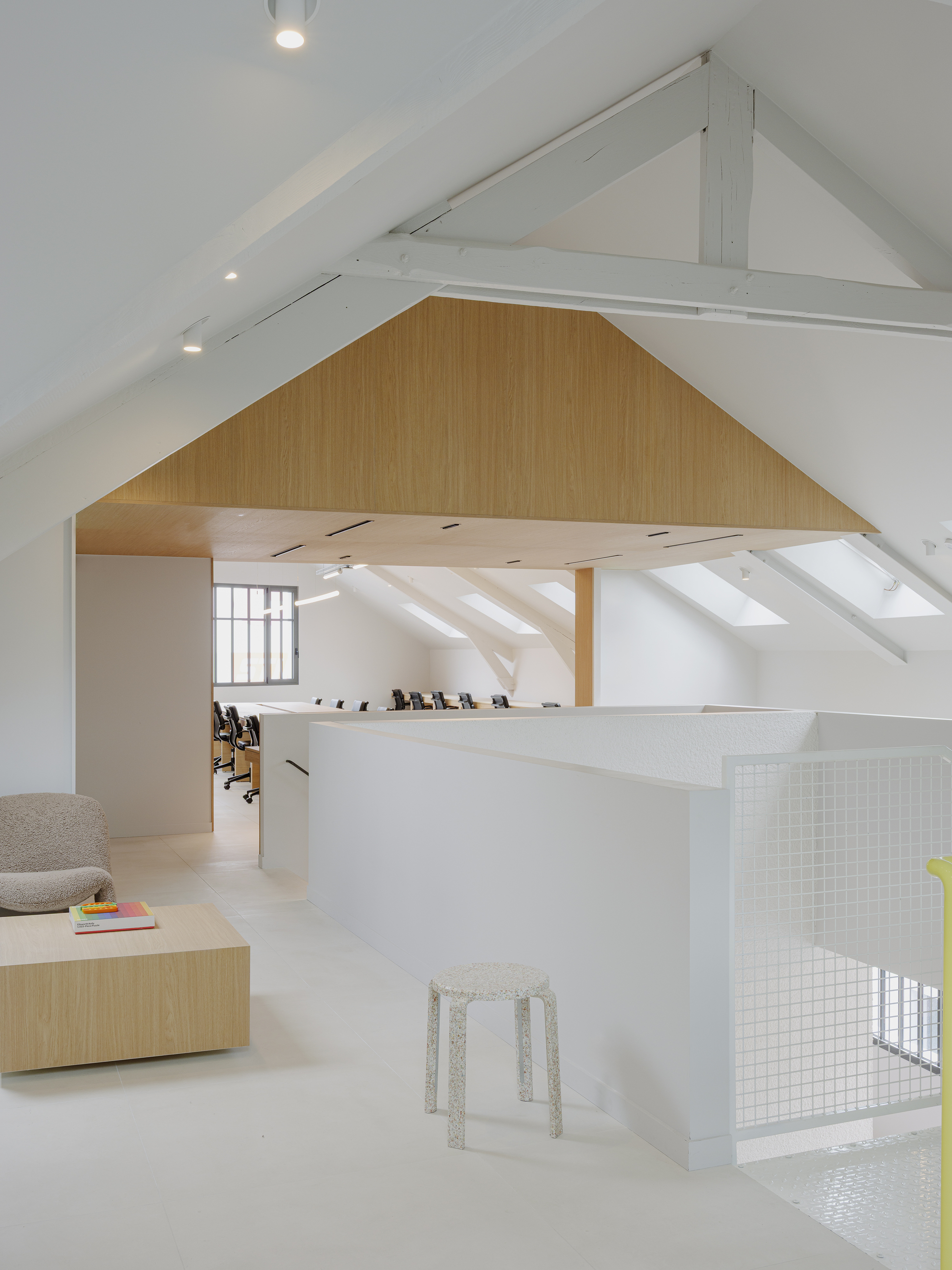 Oak-clad volume inserted beneath white-painted roof structure with exposed timber beams and skylights