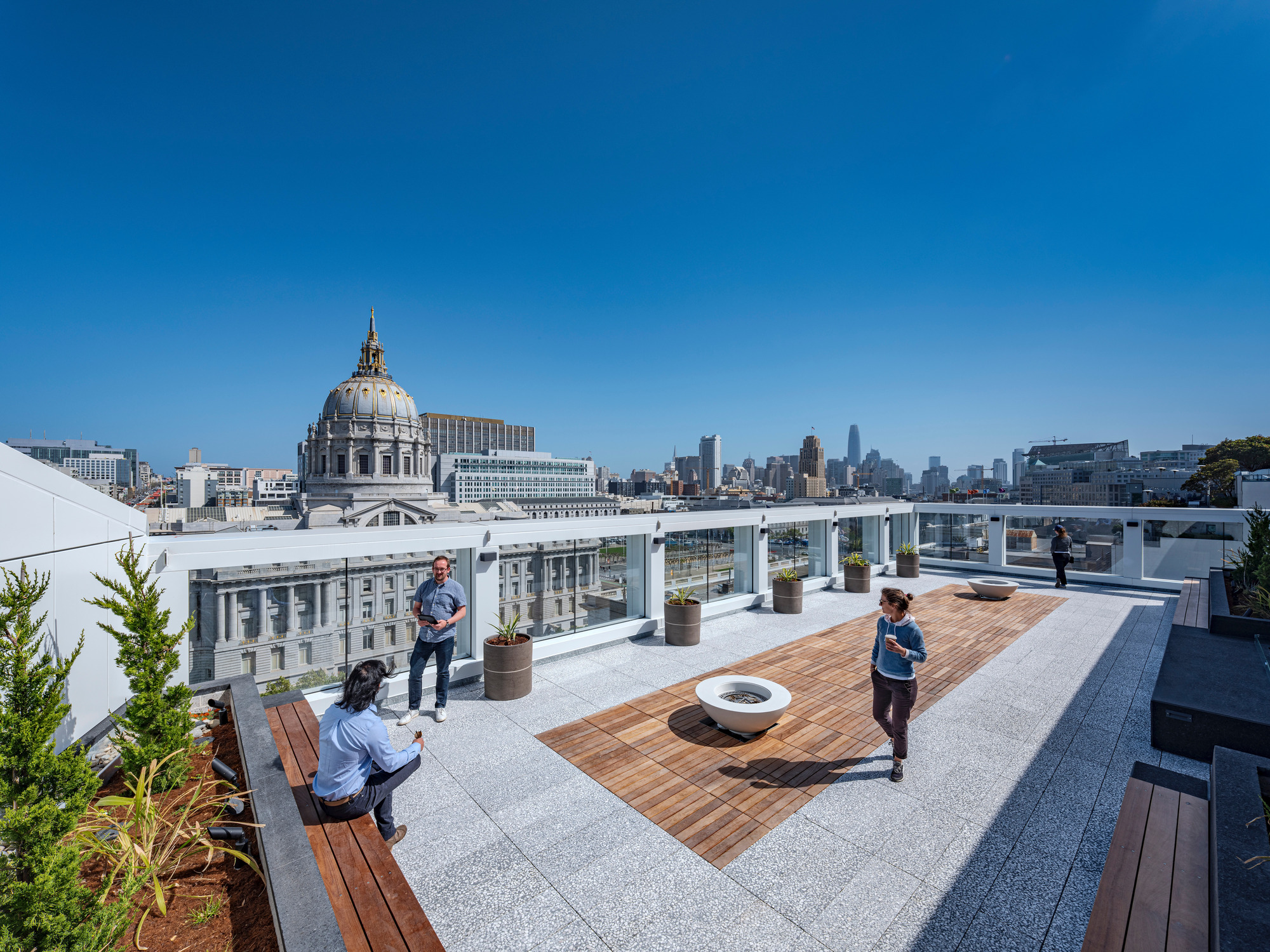 Rooftop terrace with timber decking and planters overlooking a domed civic building and skyline