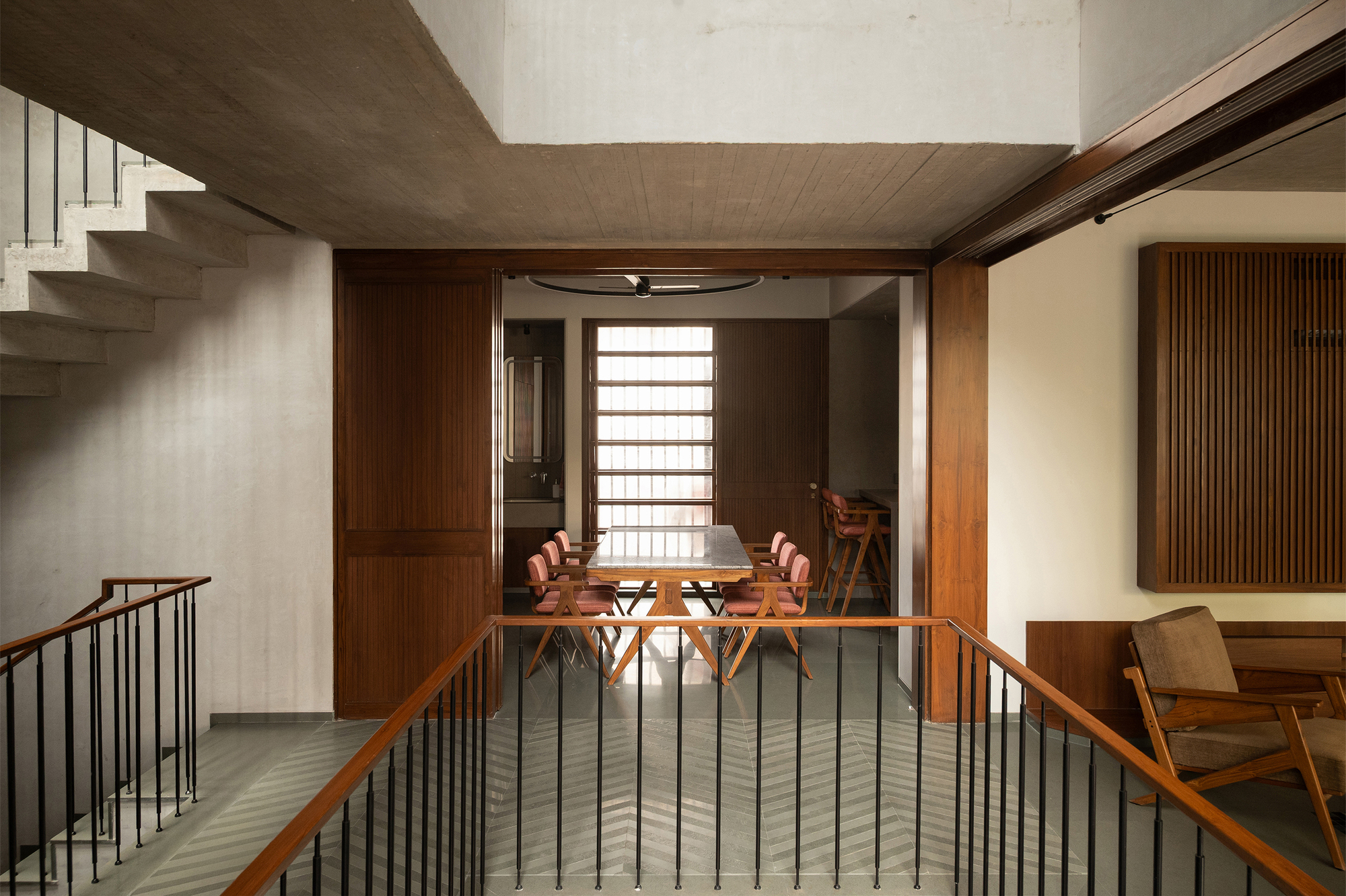 View across stair landing toward timber-framed dining area with horizontal slatted screens