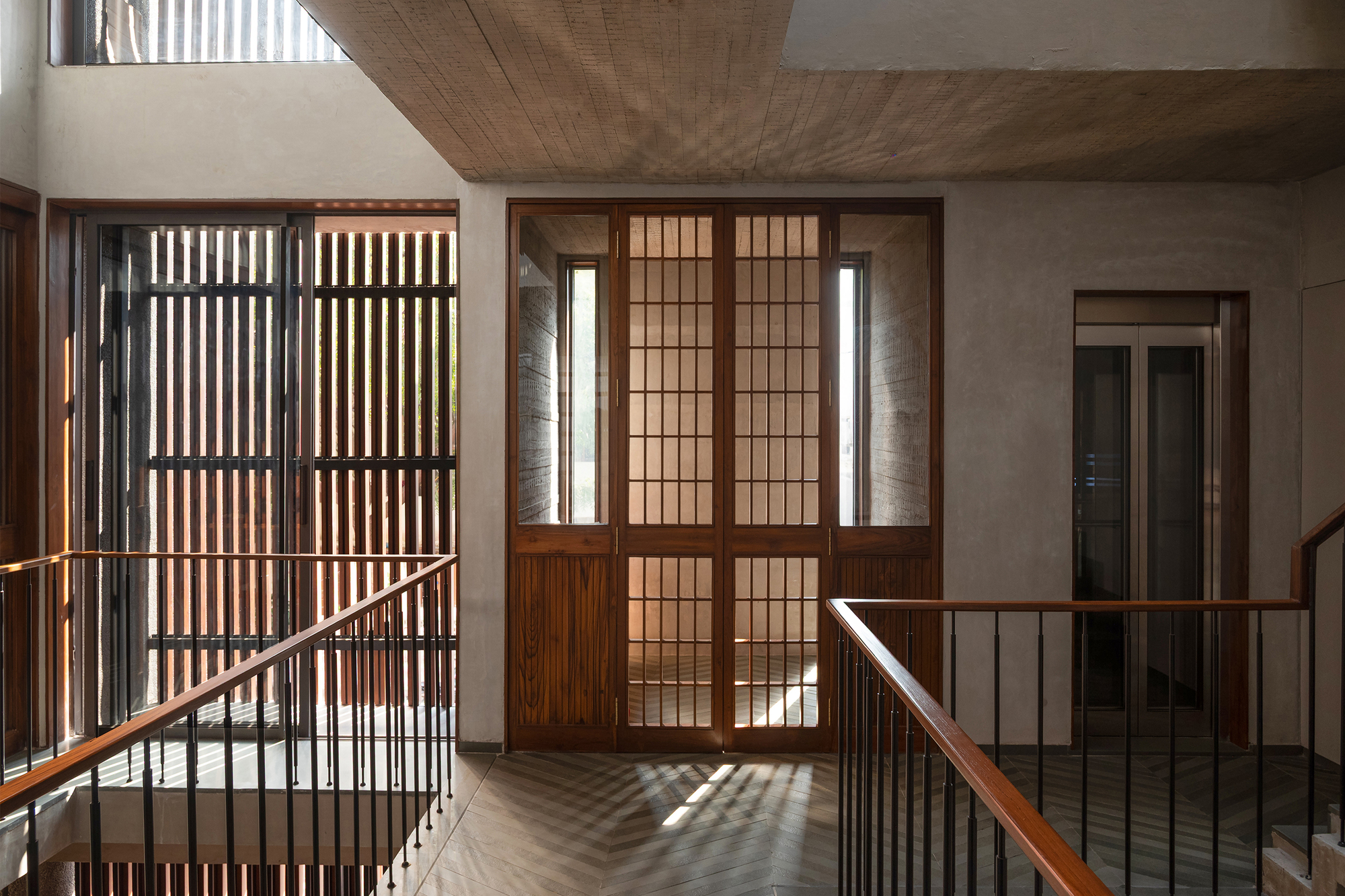 Stairwell landing with gridded timber screens and translucent sliding doors filtering daylight