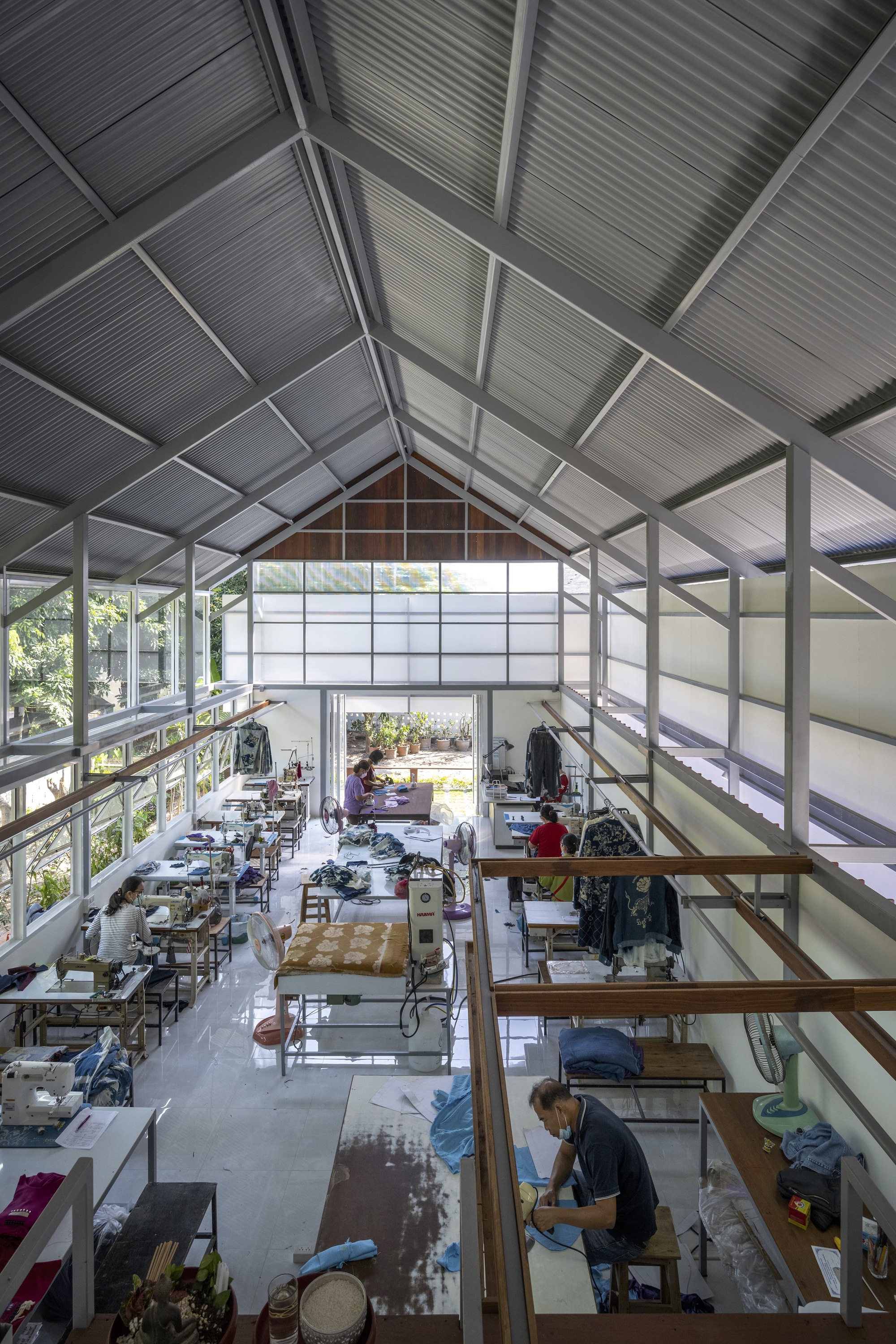 Interior view of the double-height workspace with exposed gabled roof trusses and translucent panels
