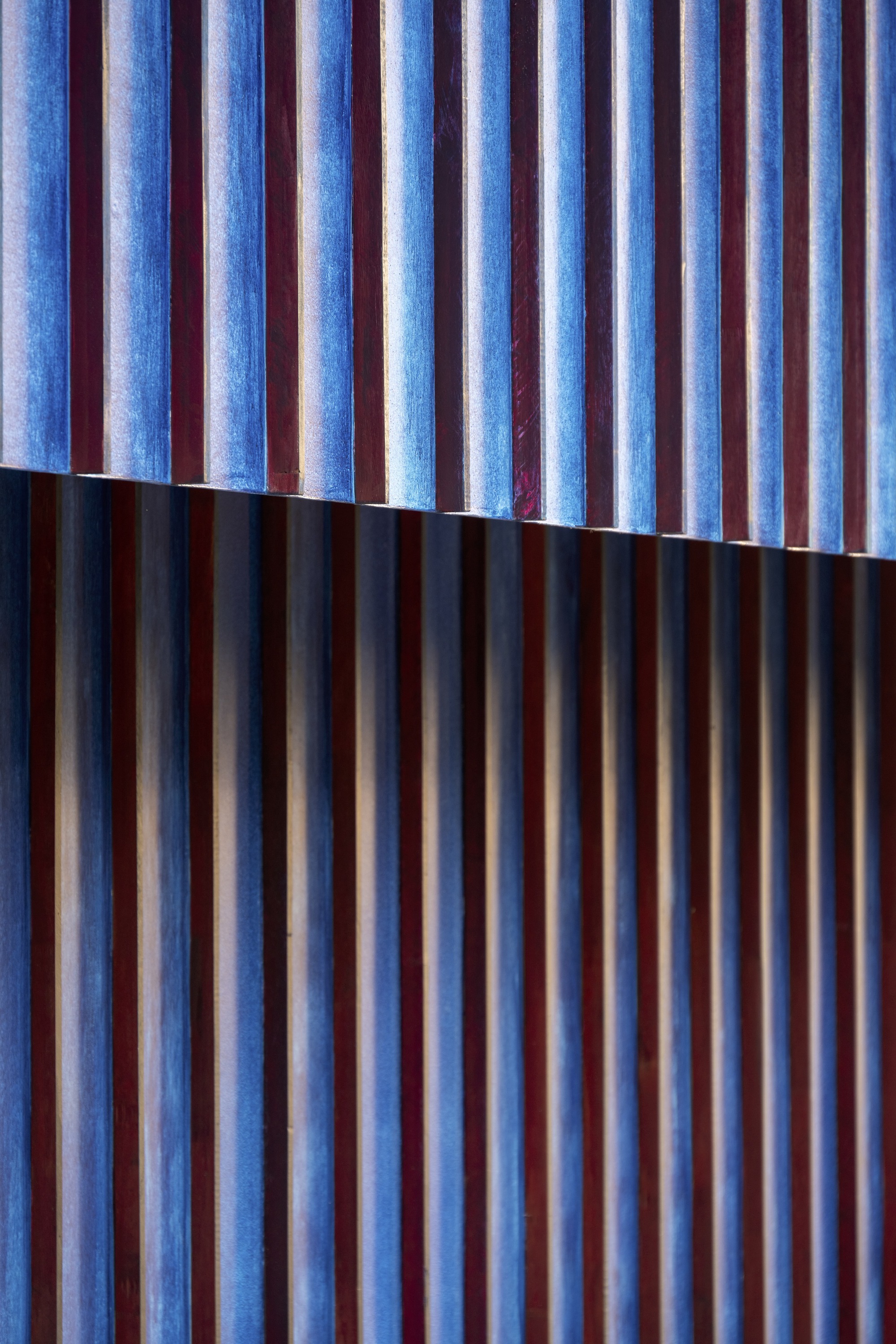 Blue-tinted vertical timber slats with a horizontal shadow line dividing the facade