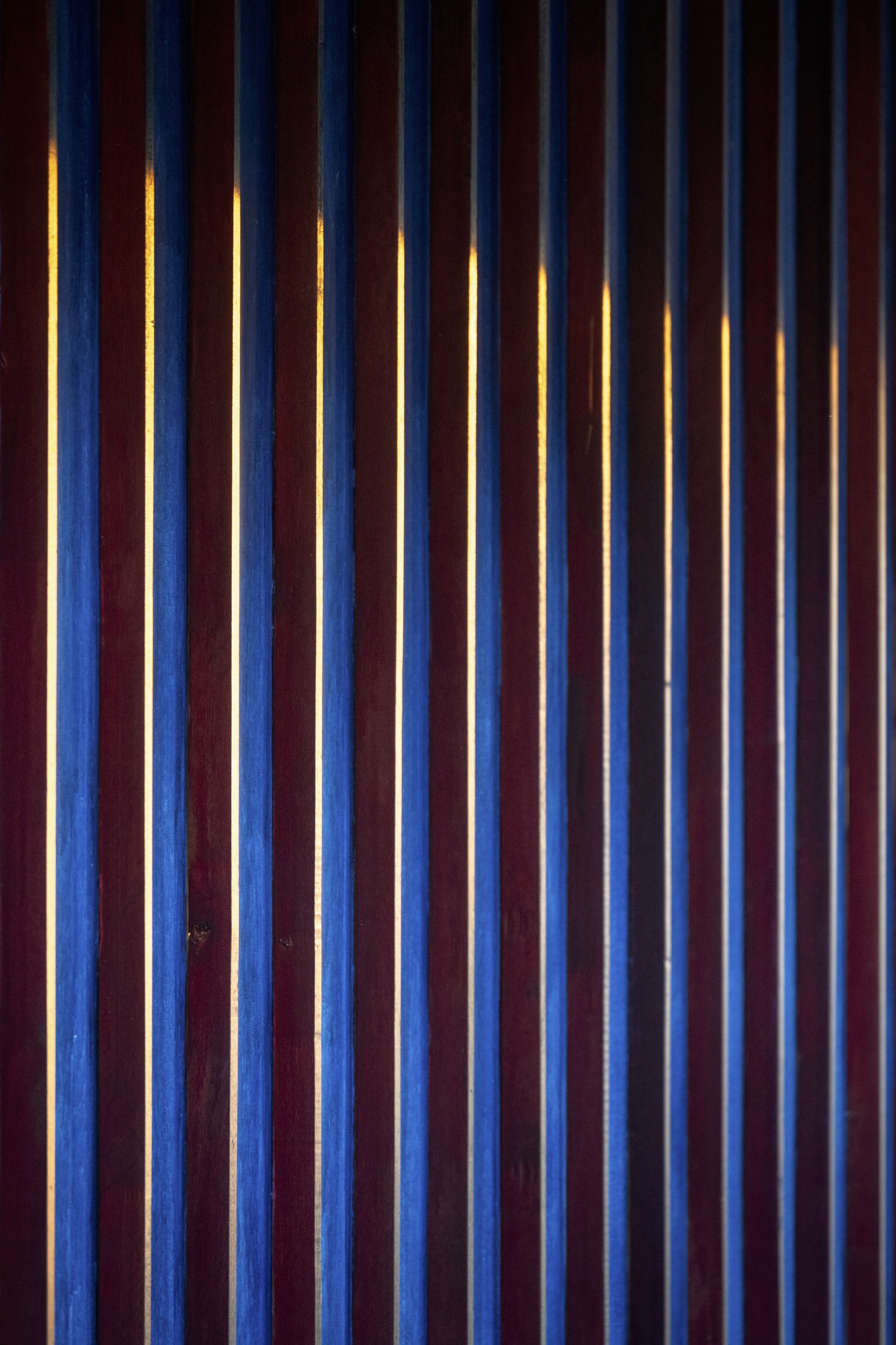 Vertical timber slat screen with warm backlighting glowing through the gaps at night