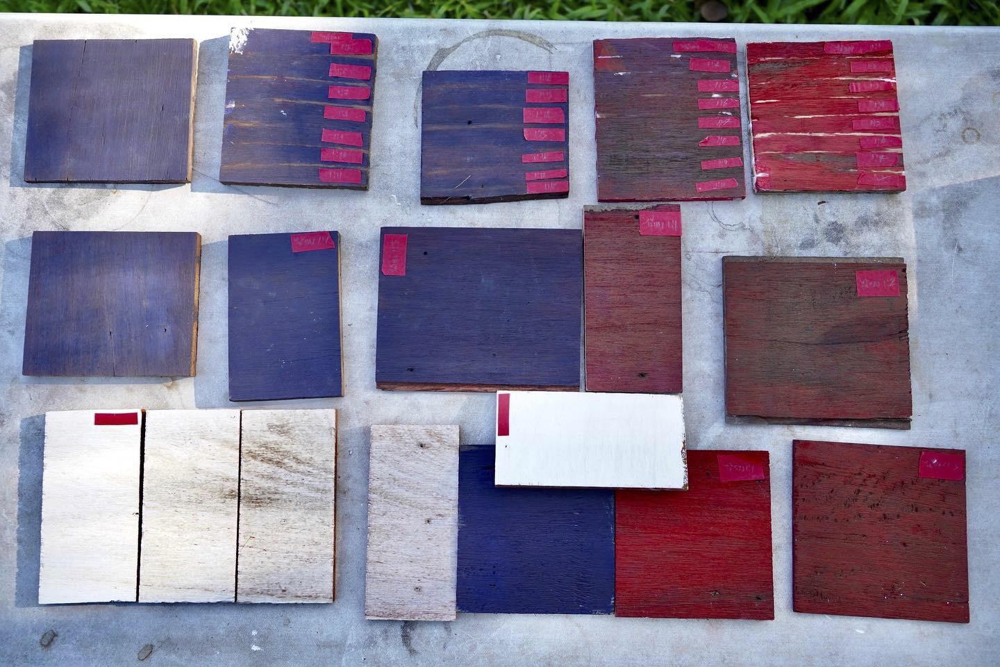 Array of wood sample boards on concrete showing gradations from dark stain to bare timber