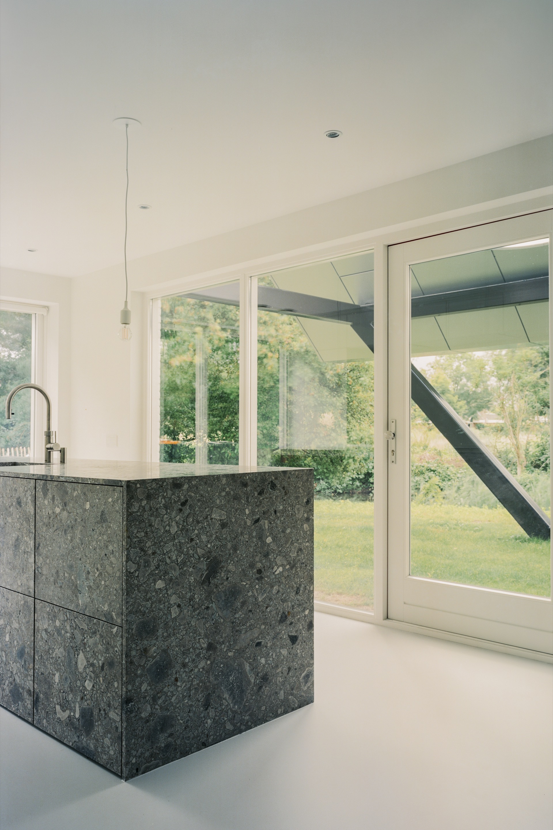 Kitchen with dark stone island and pendant light facing glazed doors to the garden