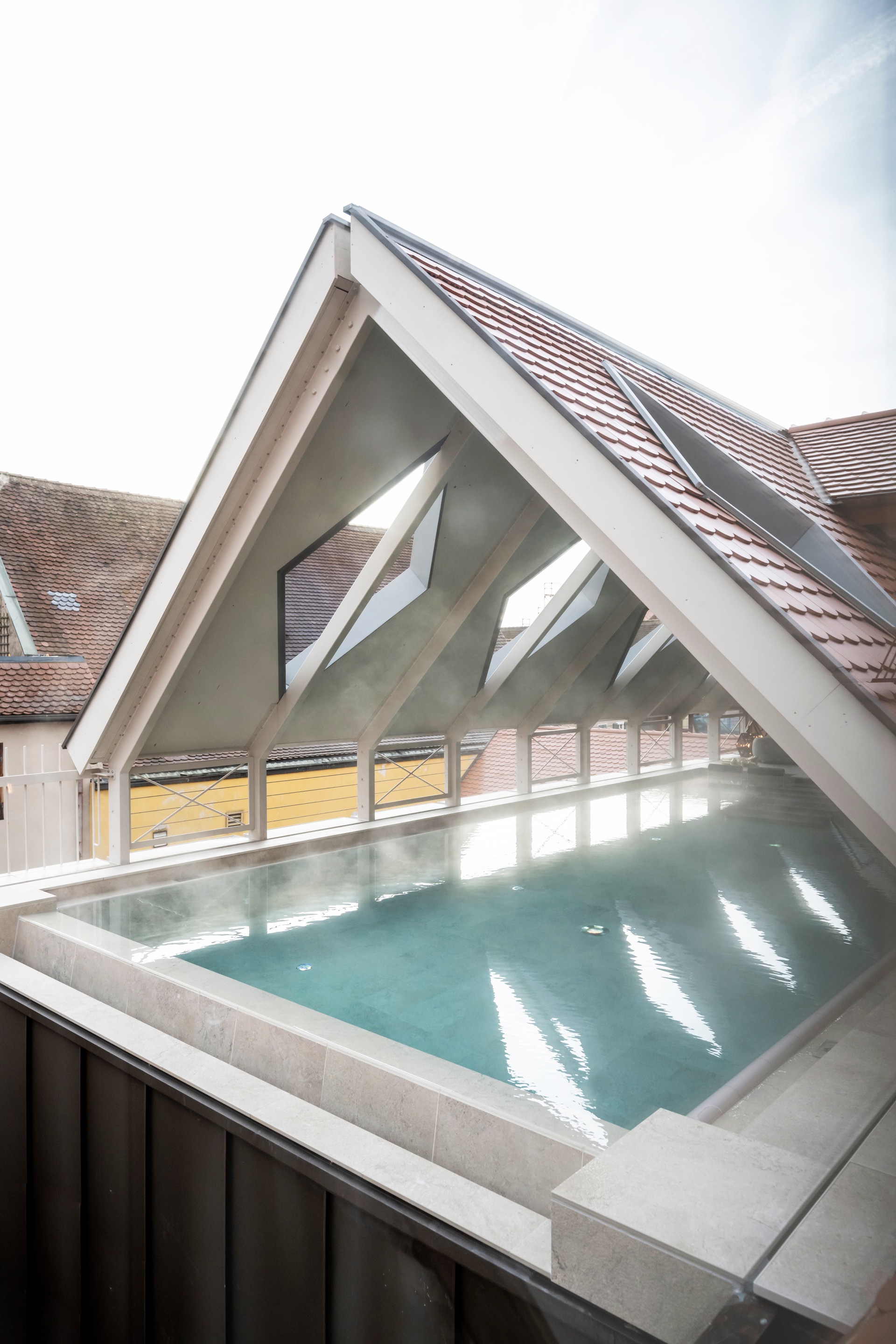 Rooftop pool with concrete edge under a white-painted timber gable and tiled roof