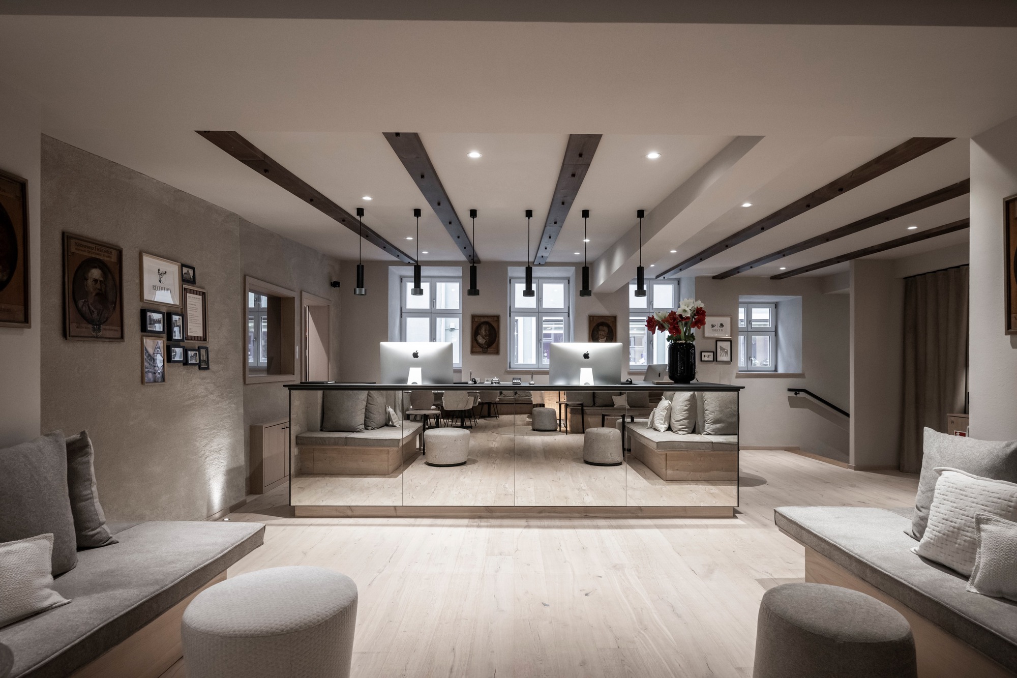 Reception lobby with mirrored front desk and symmetrical seating under exposed timber ceiling beams