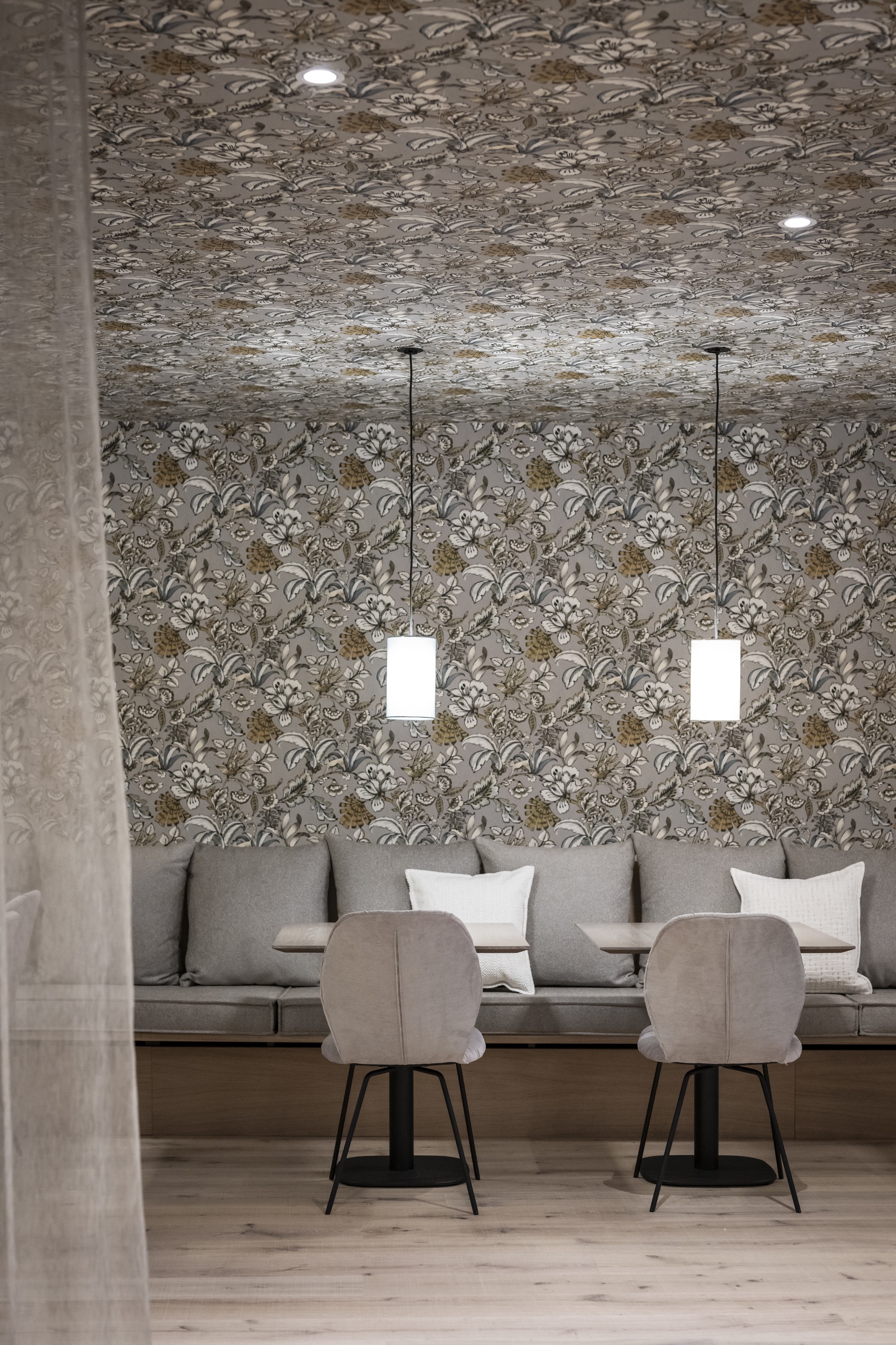 Seating niche with floral wallpaper covering walls and ceiling flanked by two pendant lights