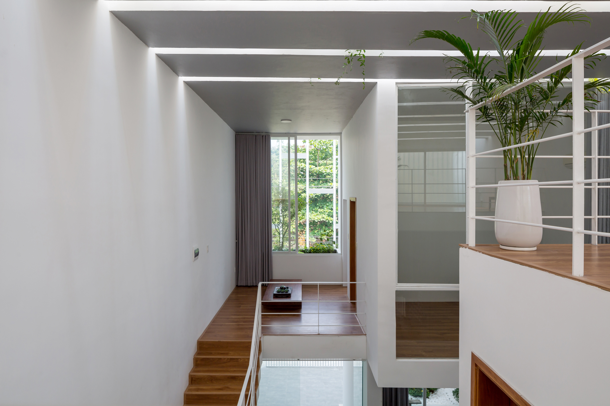 Split-level interior with timber staircase connecting bedroom to open mezzanine beneath parallel skylights