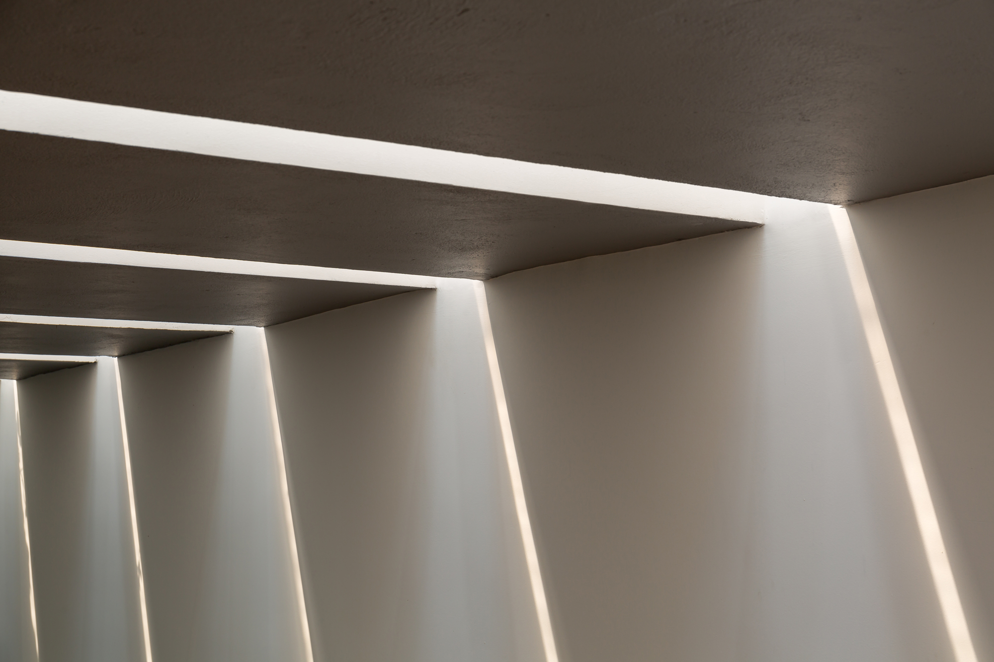 Close-up of recessed linear ceiling lights creating parallel bands of illumination across concrete soffit