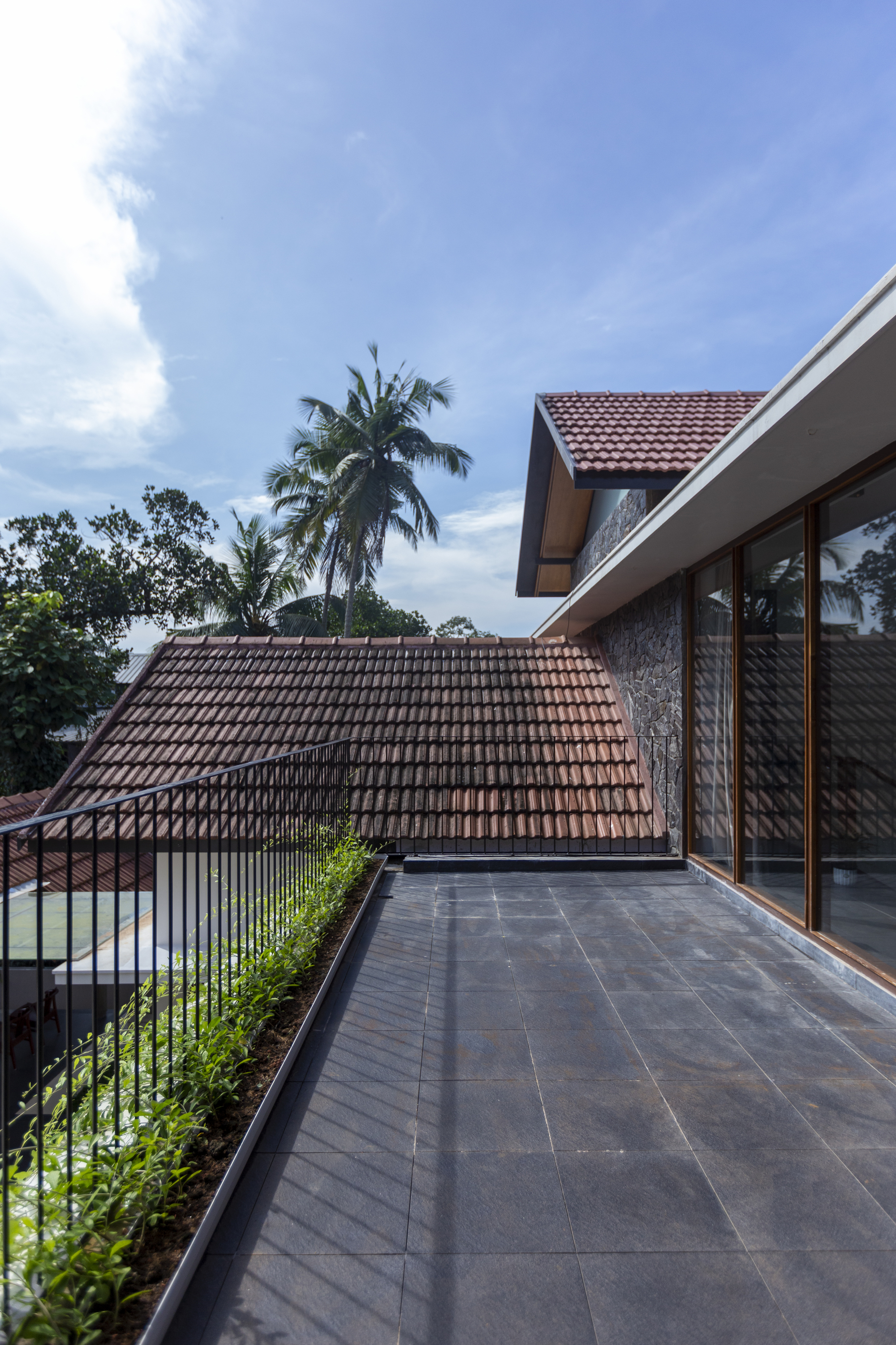 Upper terrace overlooking the clay tile roof with coconut palms against a blue sky