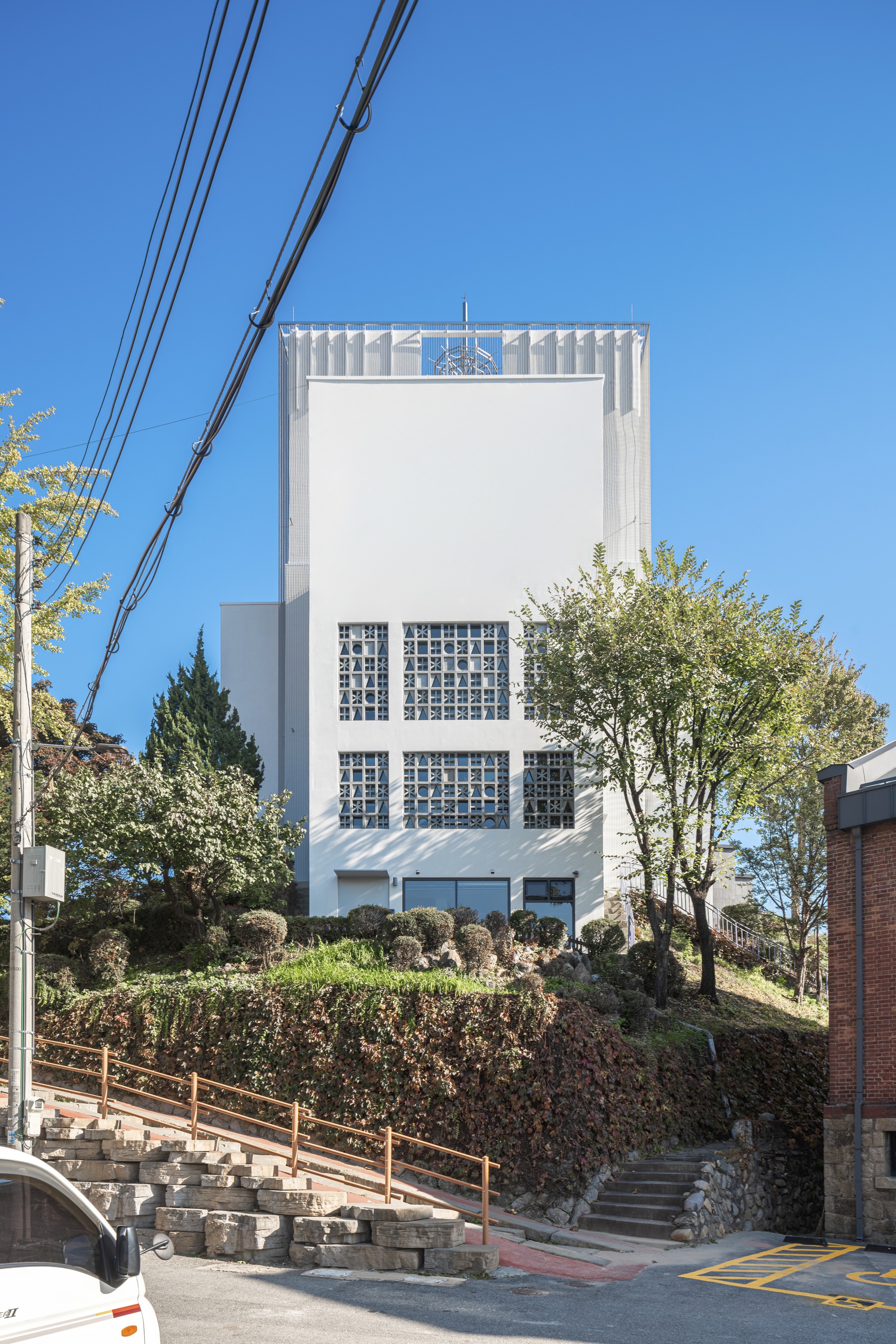 Front elevation showing glass block windows and ribbed metal canopy at the base with overhead power lines