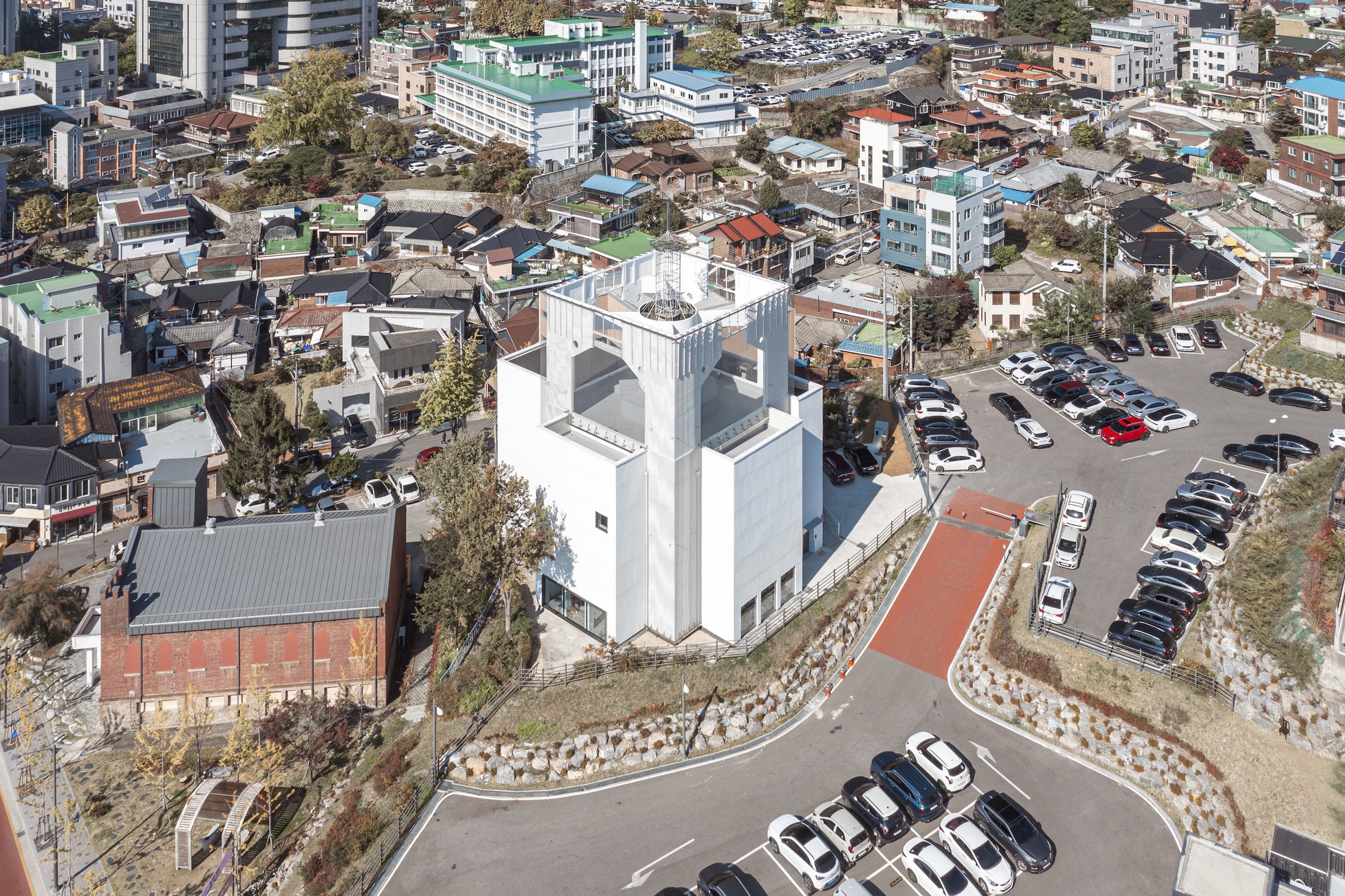 Aerial view of the white tower and adjacent brick structure surrounded by parking lots and residential neighborhood