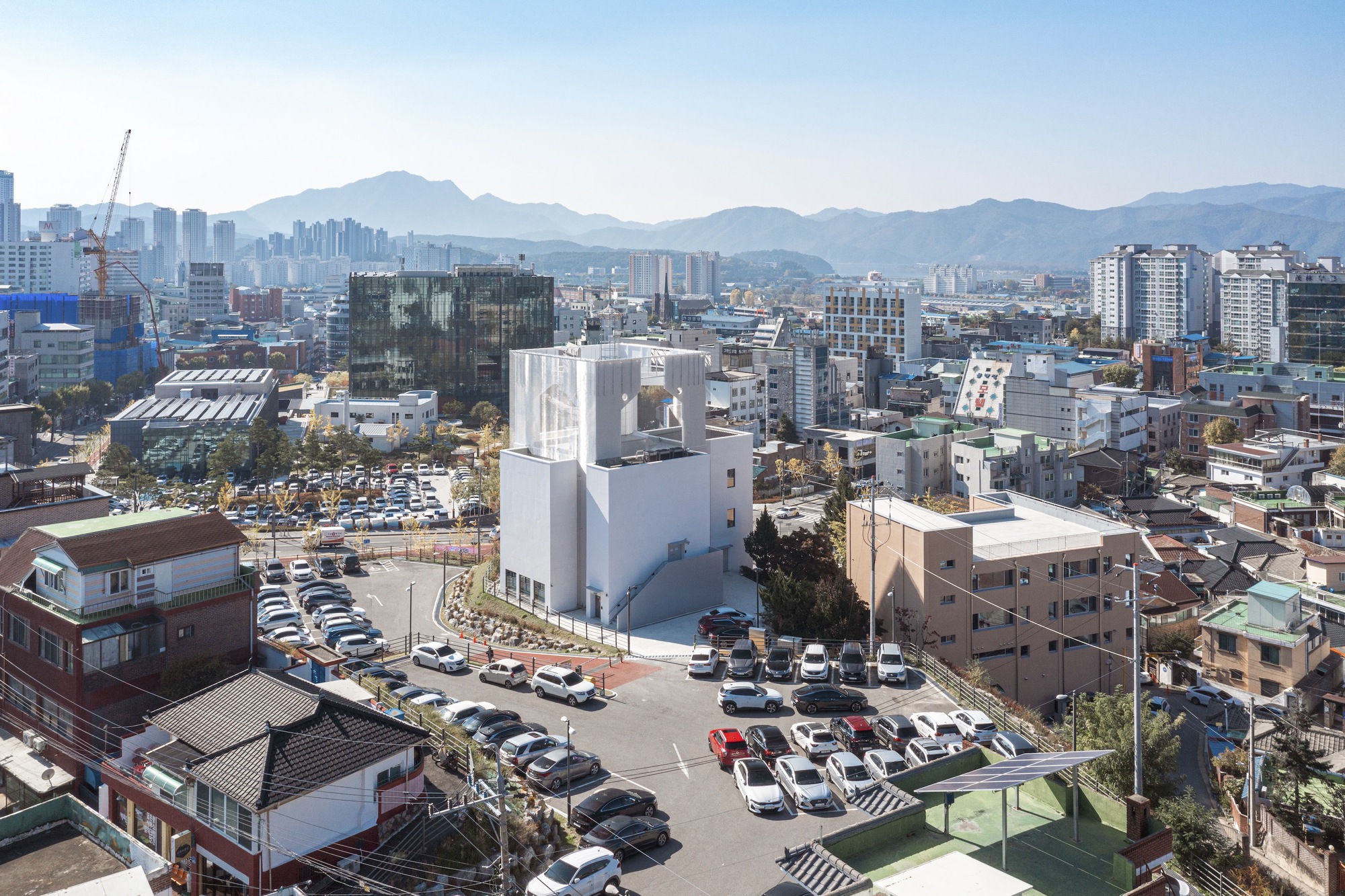 Aerial view of the white tower amid low-rise neighborhood buildings with mountains in the distance