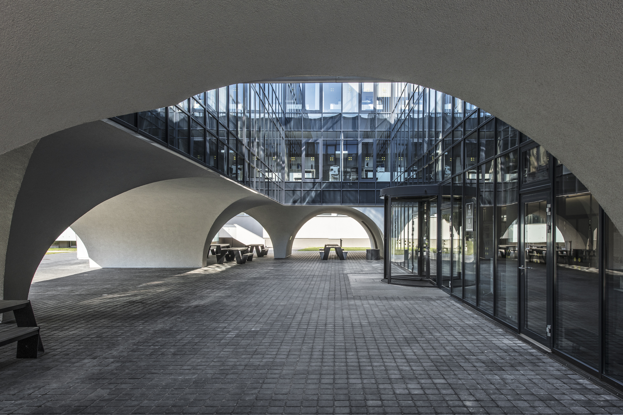 View through curved arch to glazed facade and covered passageway with layered arched openings