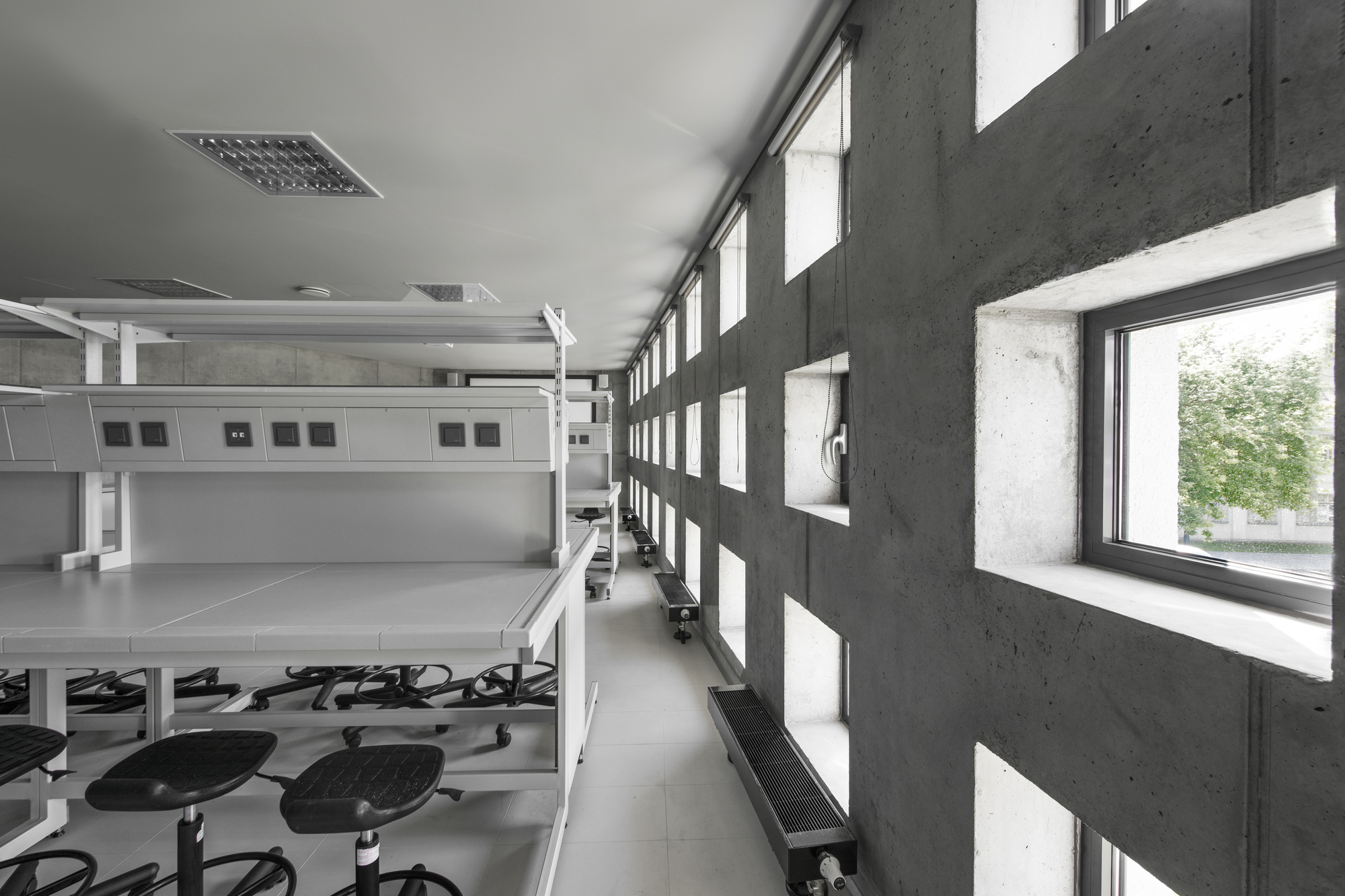 Corridor with perforated concrete block wall filtering daylight beside open workroom