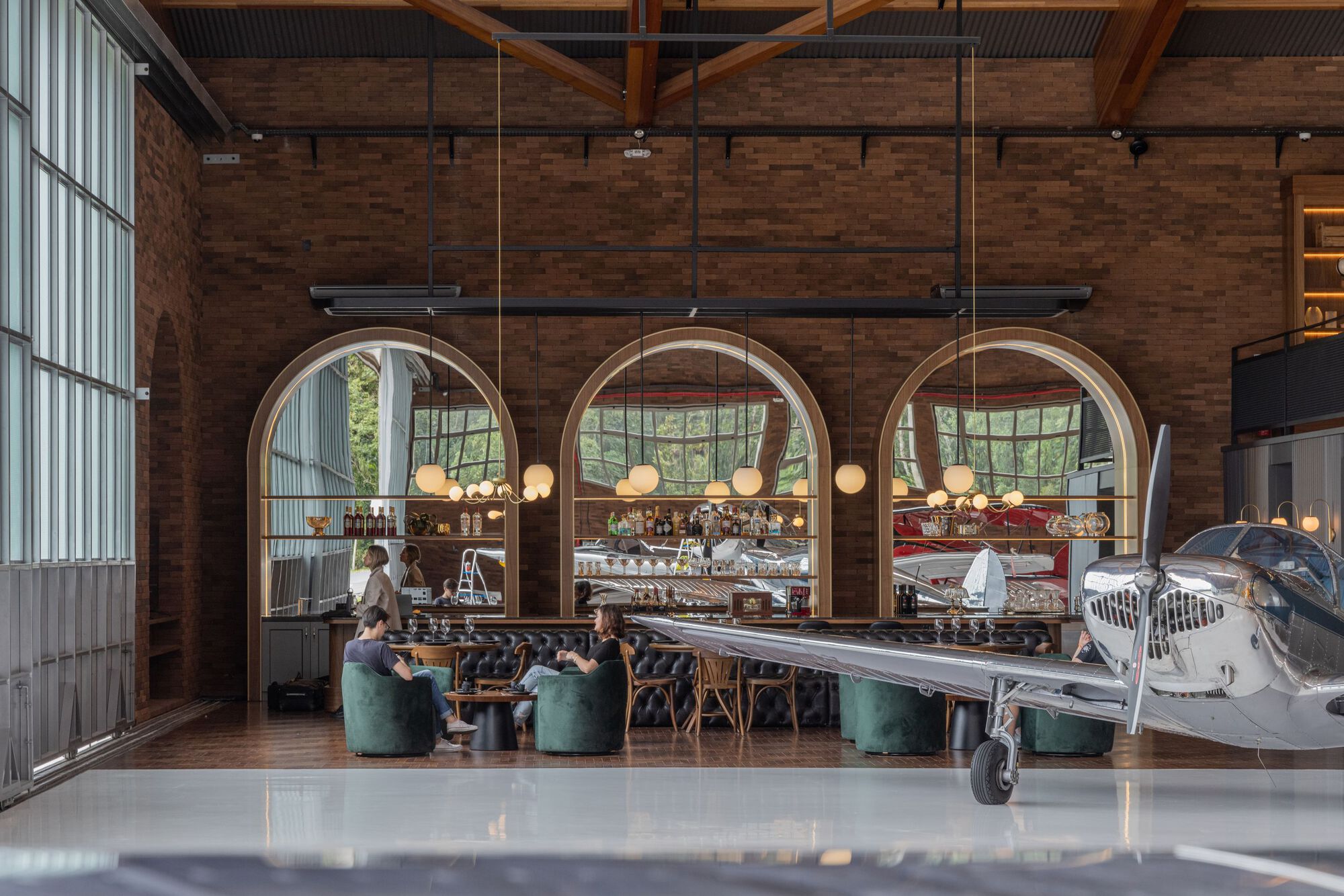 Cafe seating area with arched timber portals framing display shelves and glazed curtain wall behind visitors