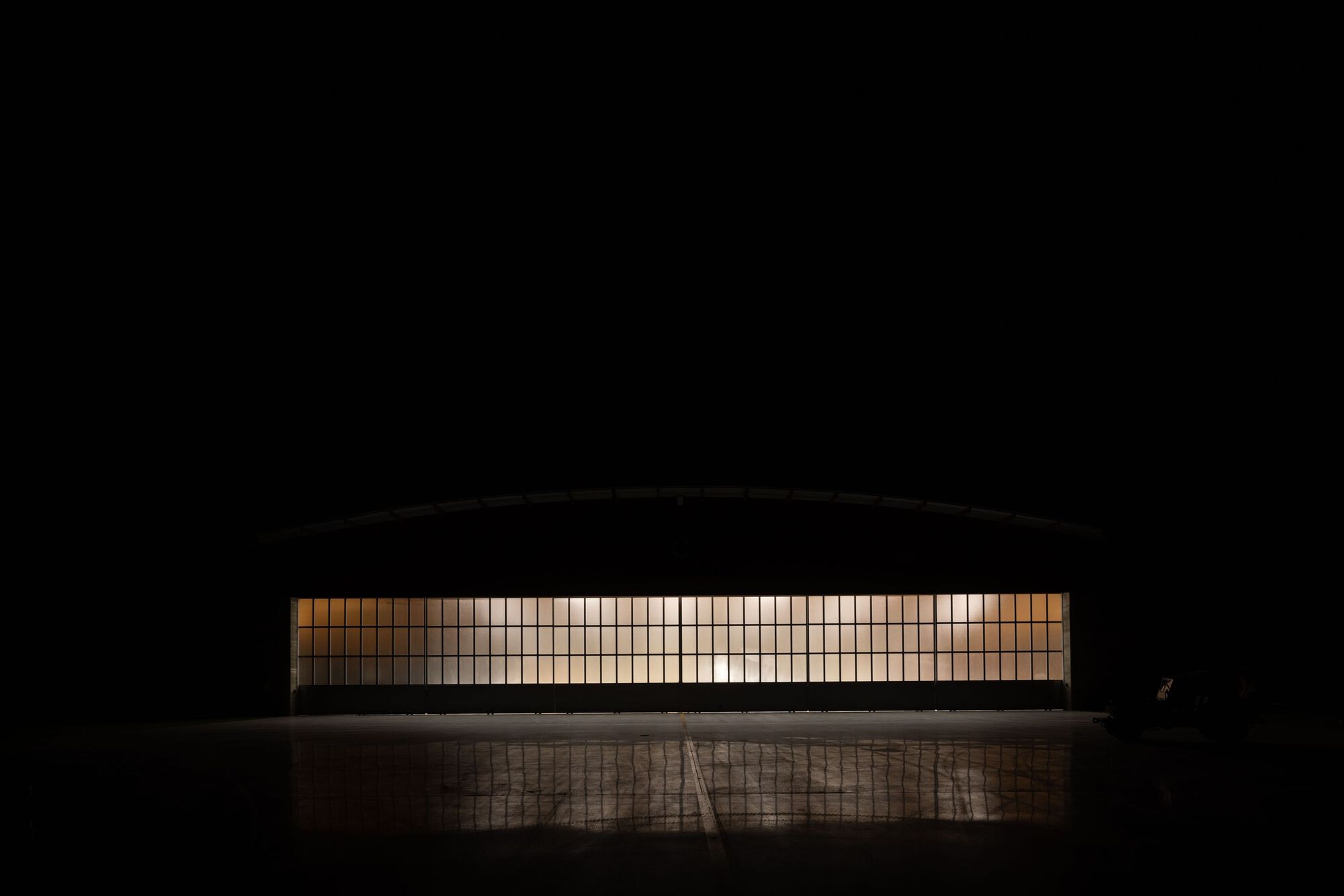 Night view of the illuminated glass block facade with a figure standing at the entrance