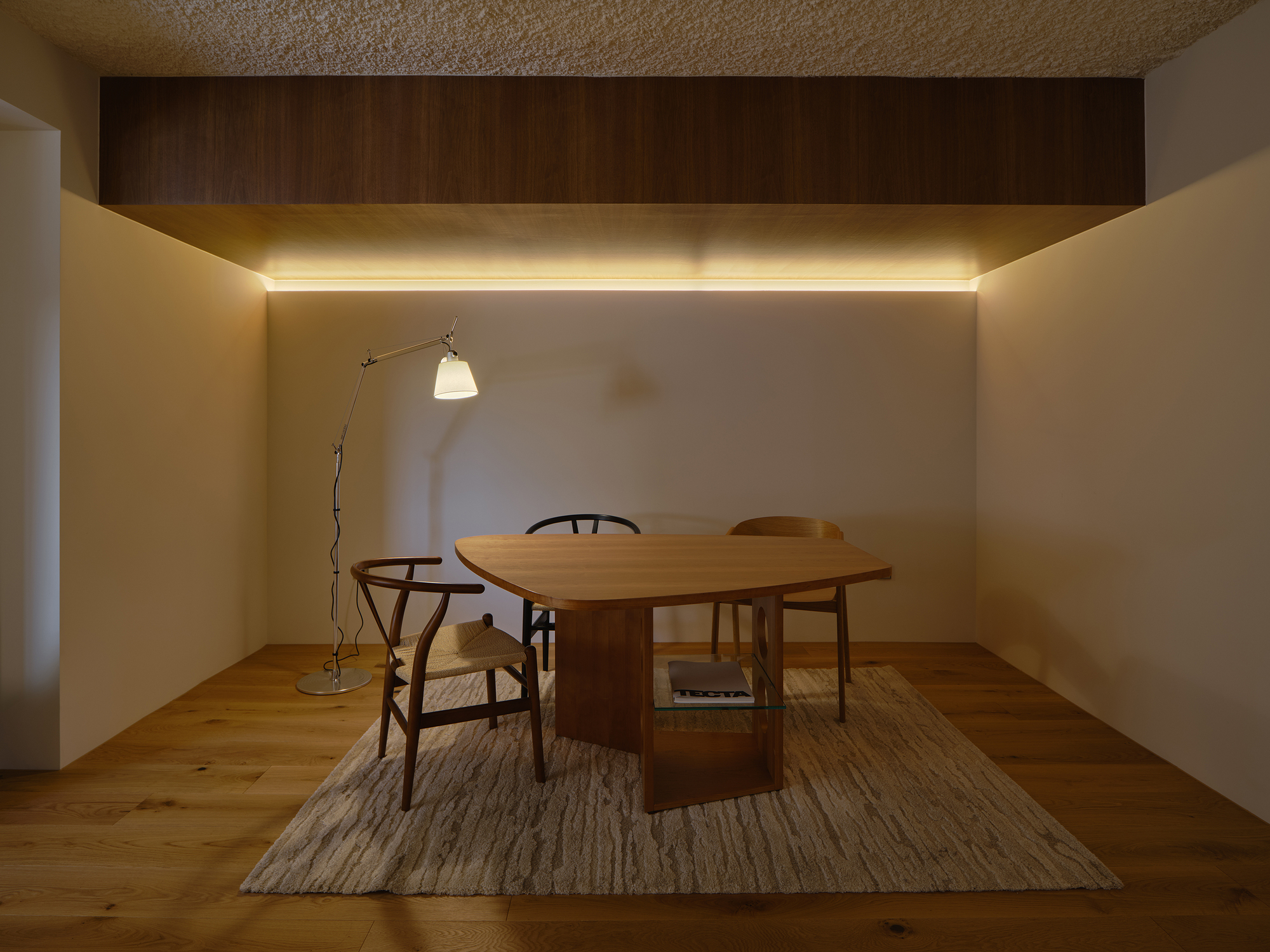 Small dining area with cove lighting beneath a recessed timber ceiling panel at night